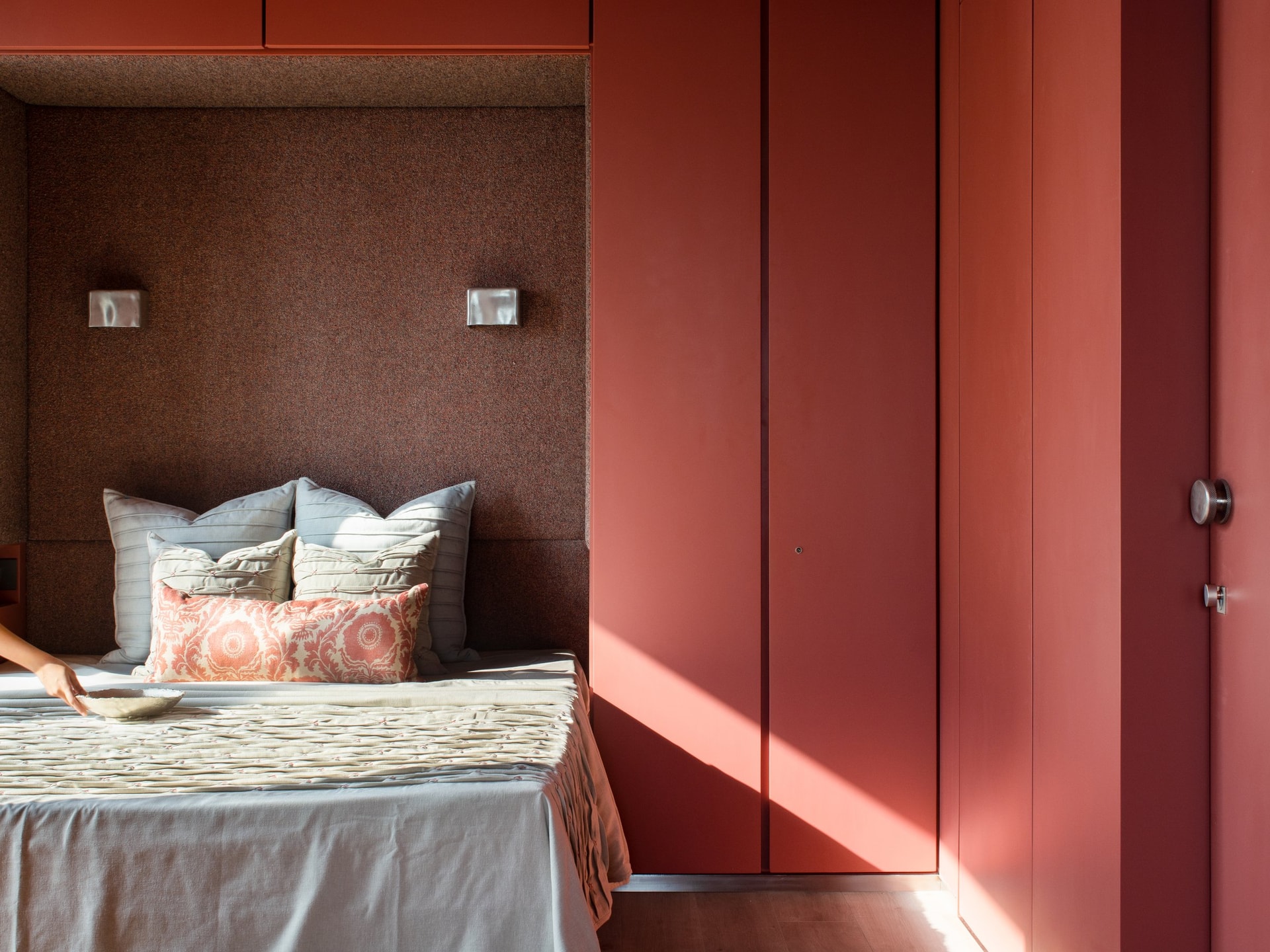 A second bedroom, where saturated terracotta envelops wardrobes, doors, and headboard wall