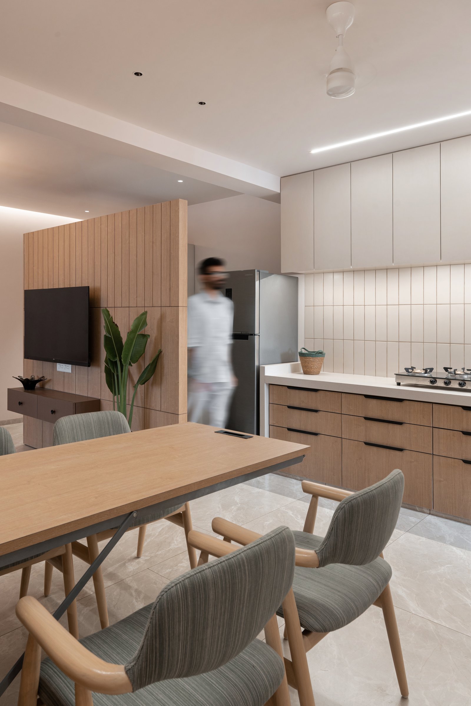 The dining area opens to the kitchen, with a wood-clad partition defining the boundary between social and service zones