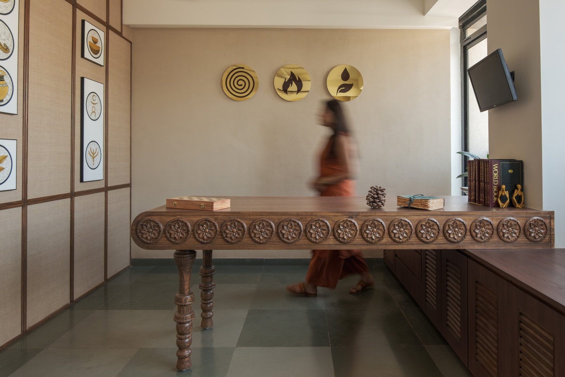 The reception and waiting area, where three golden discs etched with the Tridoshas anchor the wall above a carved teak table