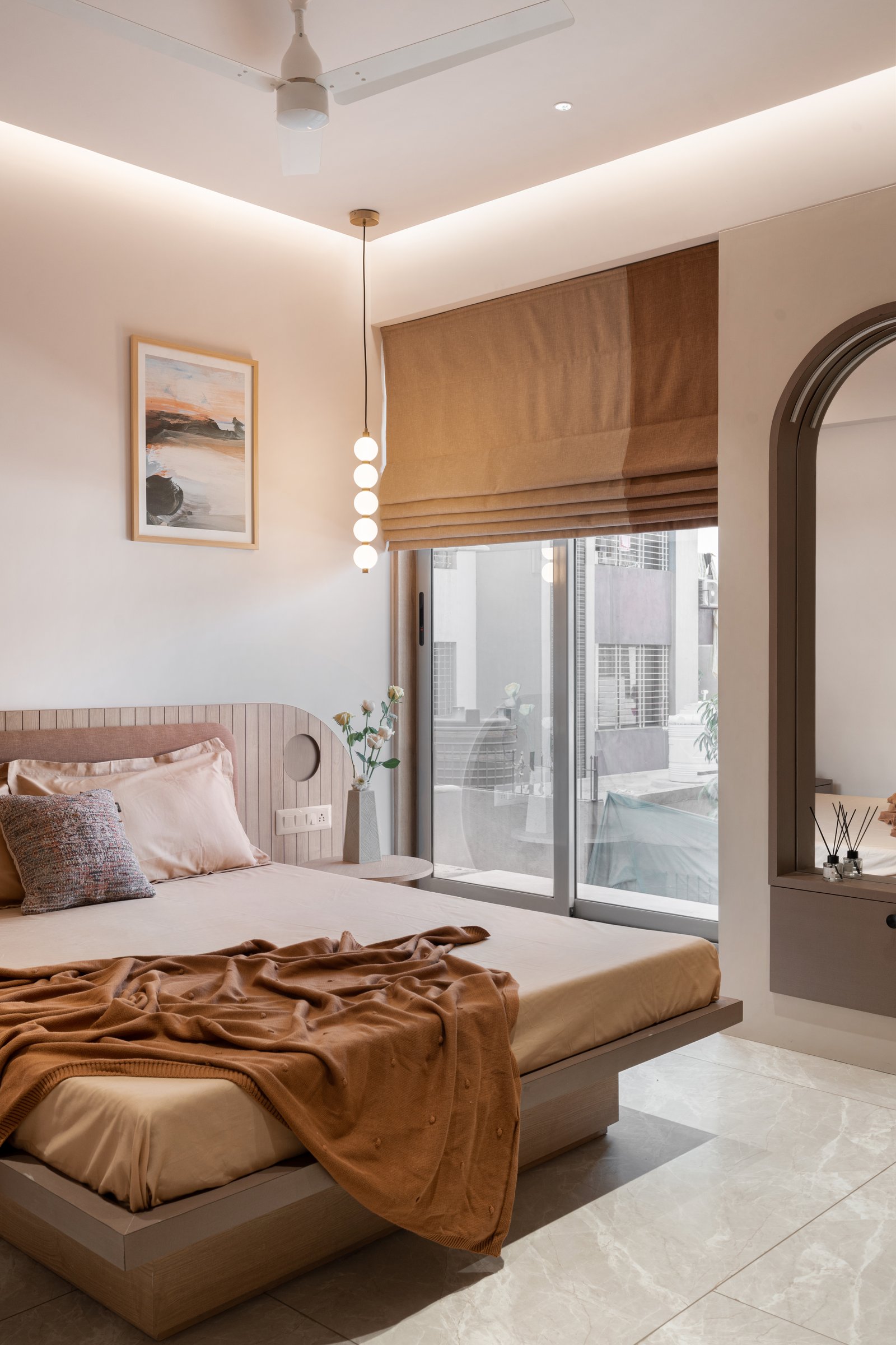 The master bedroom, where a reeded wood headboard meets a soft upholstered panel beside an arched mirror set into the wall
