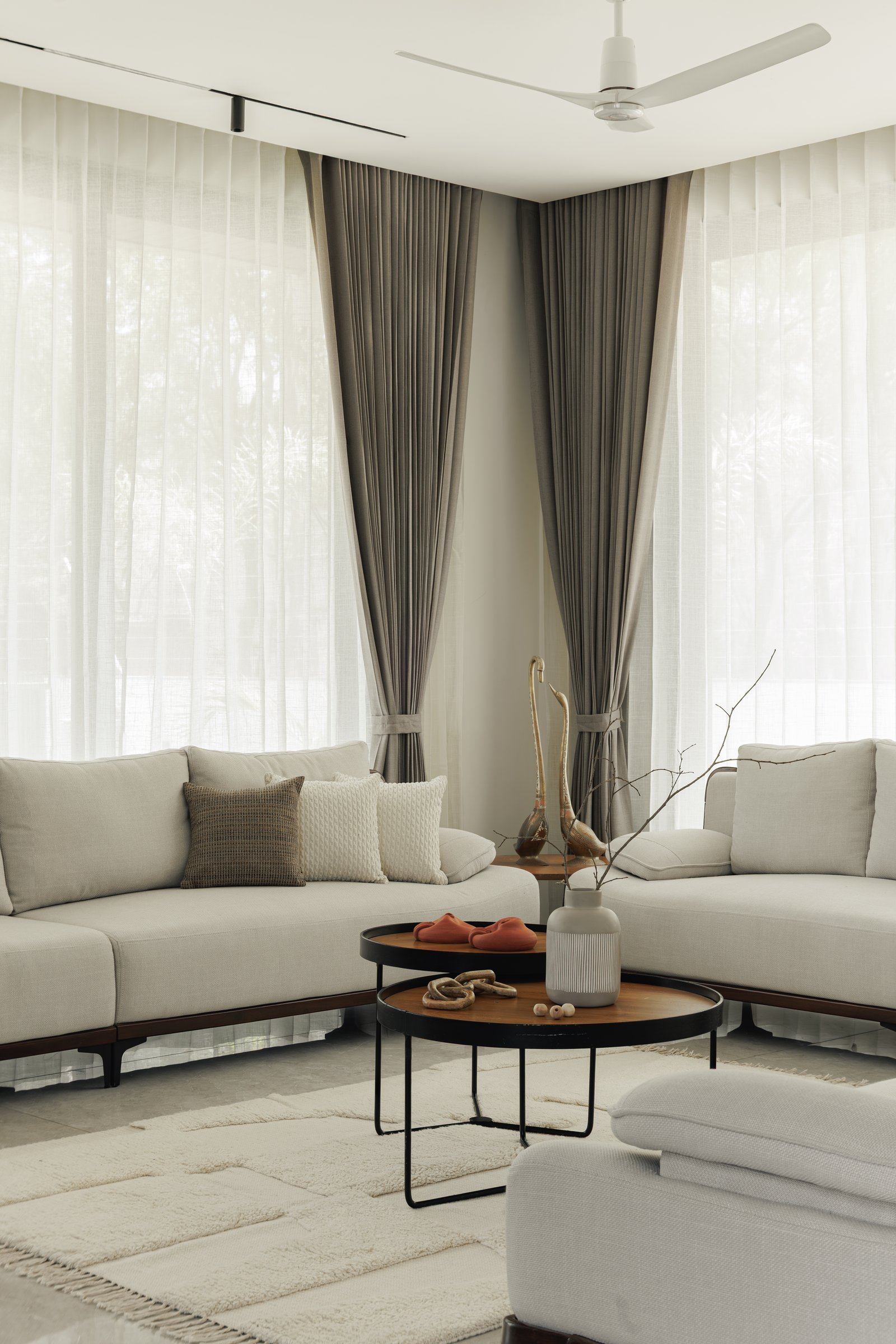A closer view of the seating, the curved sofas turning gently inward around a pair of low black-rimmed tables