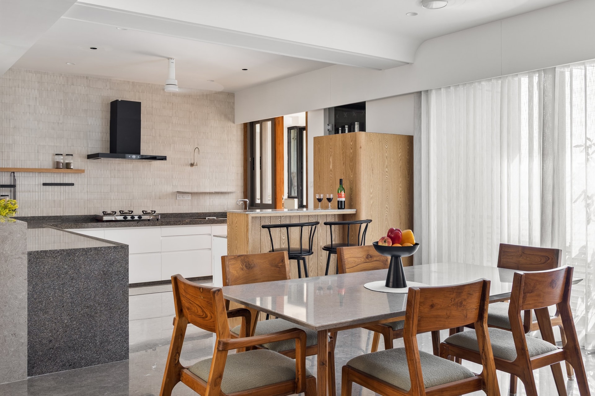 The kitchen and dining, where handle-less white cabinetry meets a pale stone table and solid wood chairs