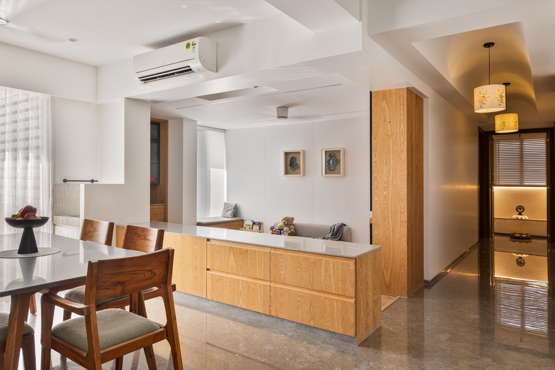 A wood-fronted sideboard divides the dining from a small window-side nook, with the puja passage beyond