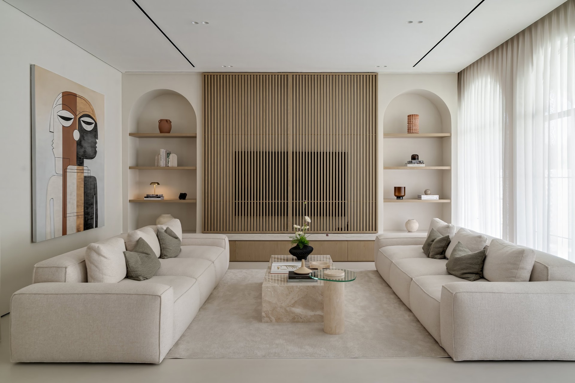 The living room, where a slatted oak wall conceals the television and arched niches echo the façade's openings