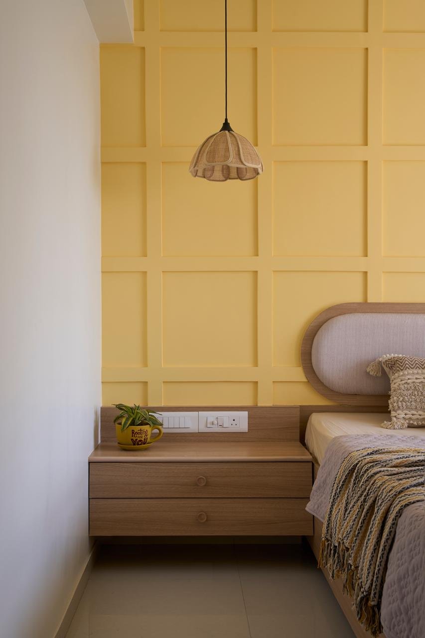 The bedside detail, where the panelled wall's grid meets floating oak drawers in a study of quiet proportion