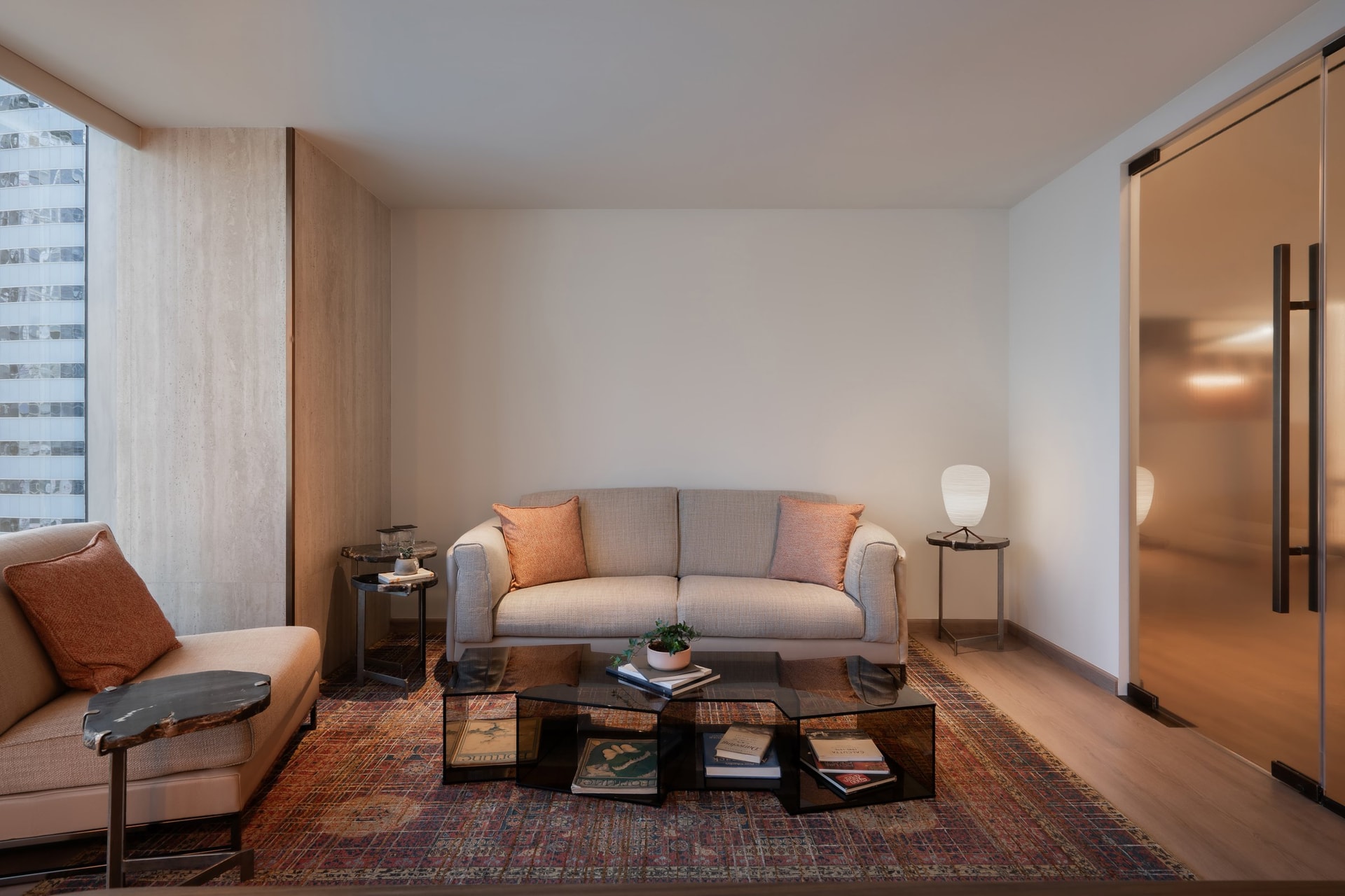 The waiting lounge, where a travertine window recess and a patterned rug soften a room otherwise held in pale neutrals