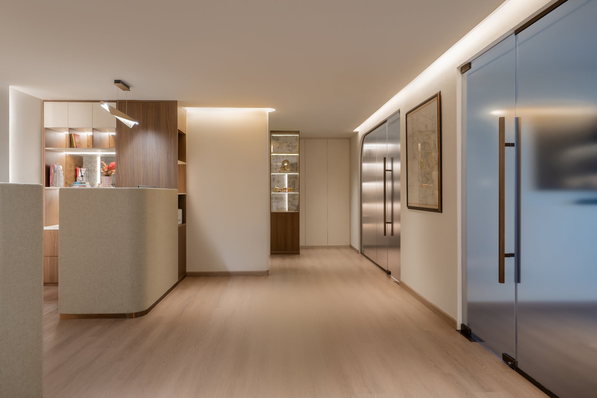The reception corridor, where curved cabinetry, a display niche, and concealed lighting establish the interior's quiet rhythm