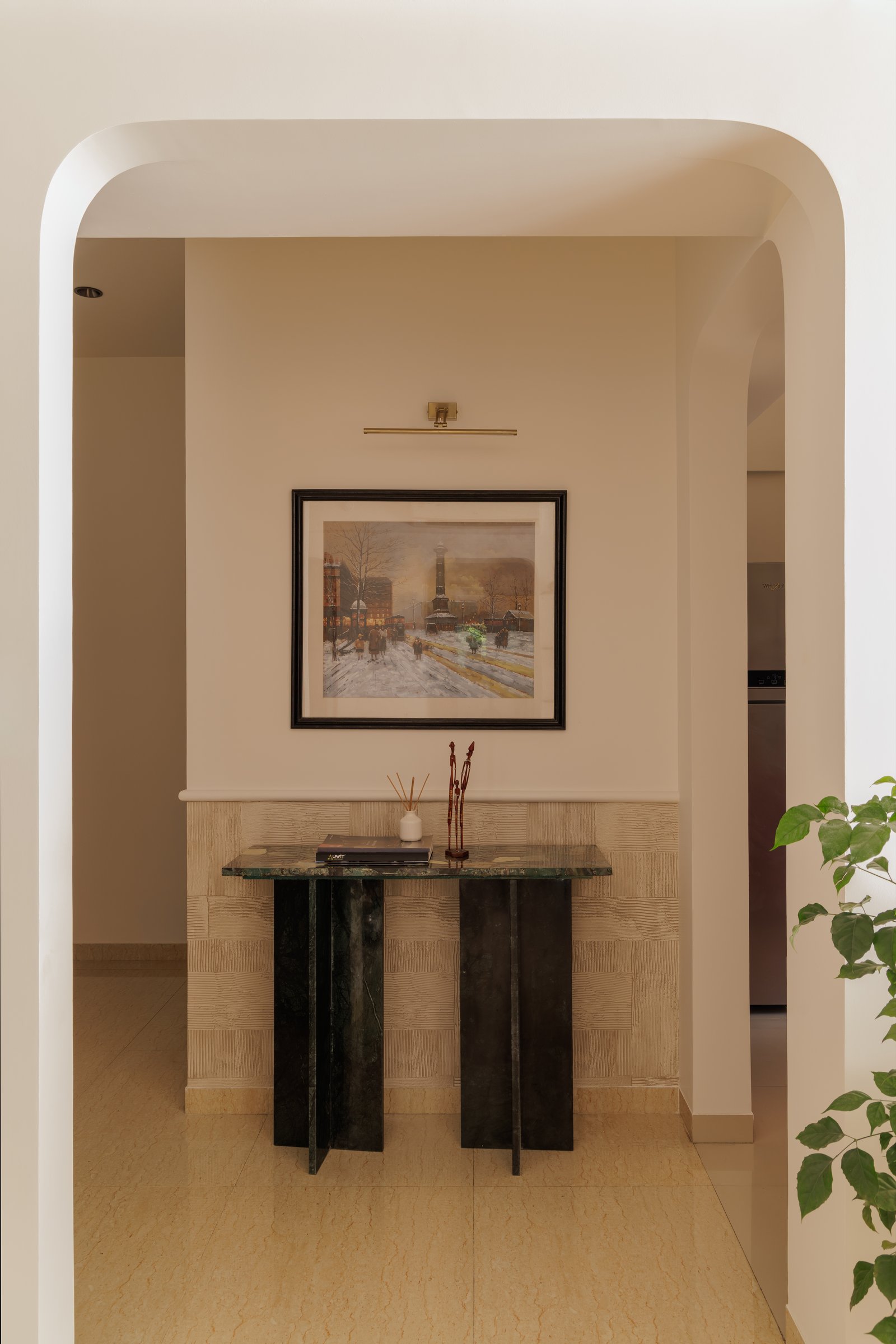 The entry, where a green stone console and softly arched opening set the tone for the home's material and cultural register