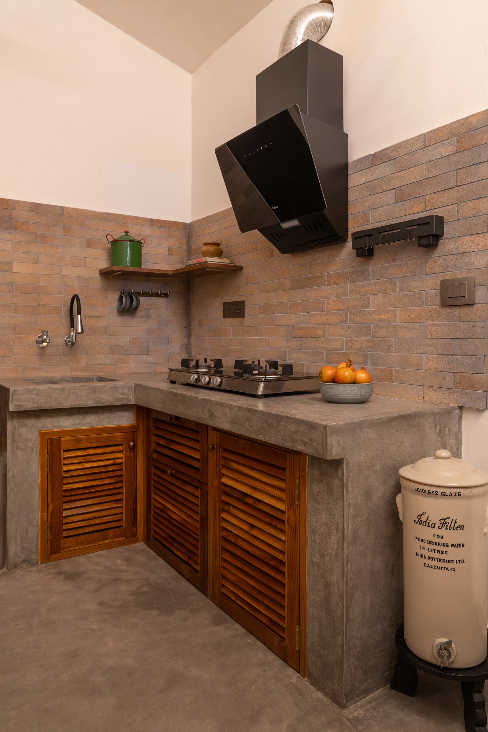The kitchen counter, where teak louvered cabinetry and an integrally cast oxide sink resolve the working wall into a single continuous plane