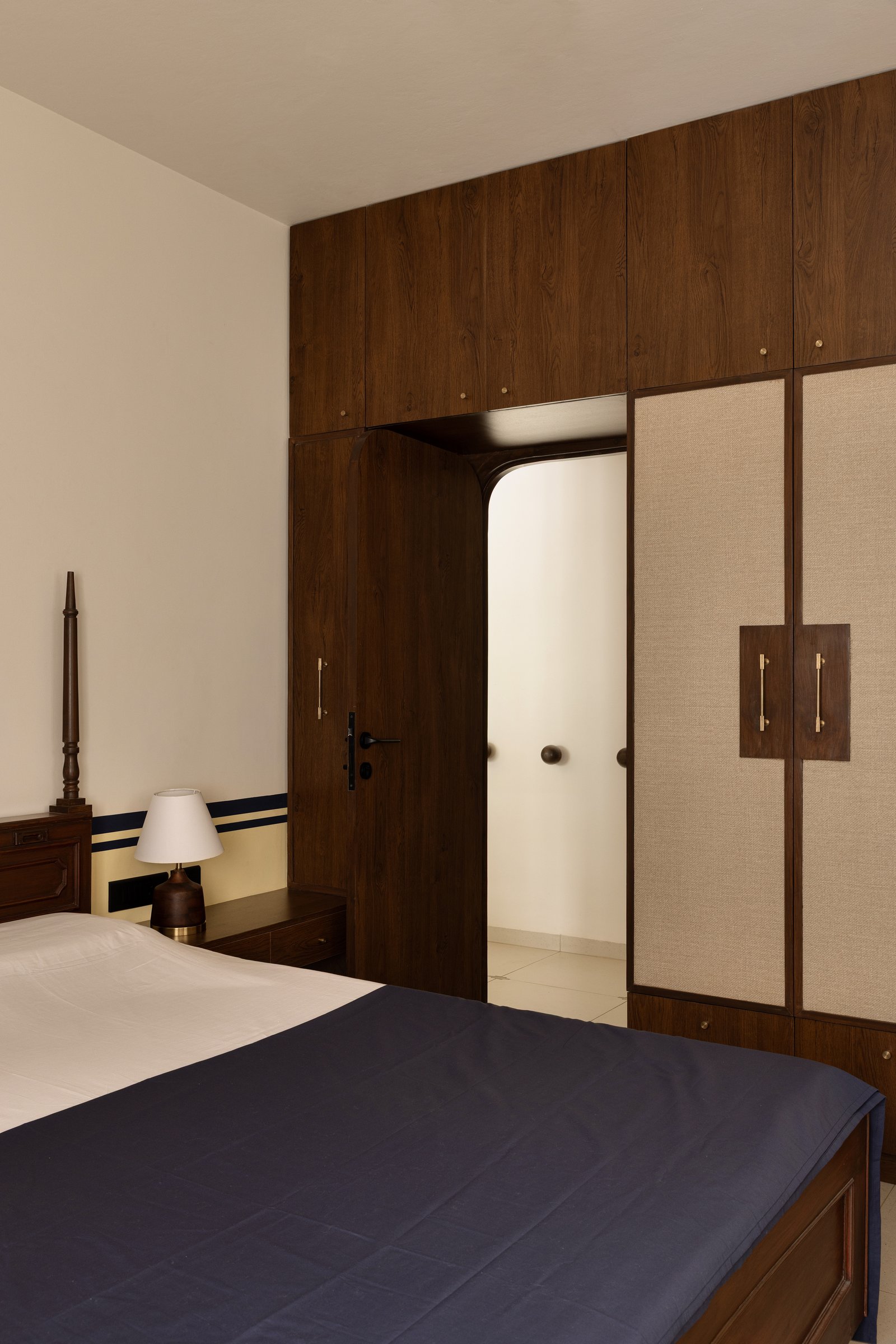 The master bedroom's wardrobe wall, composed as a piece of architecture with cane-and-wood inserts and brass hardware