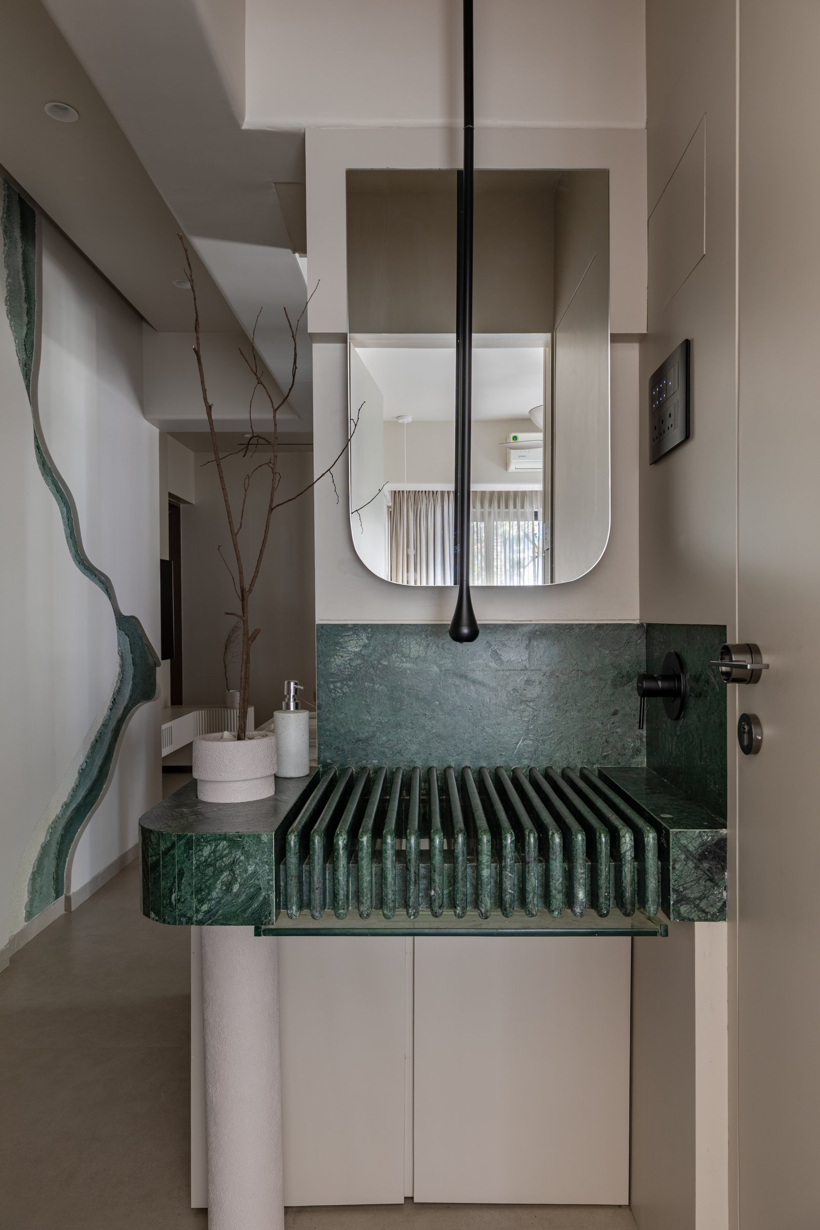 The sculpted green marble basin, its ribbed slats concealing a removable glass panel and a hidden drain beneath