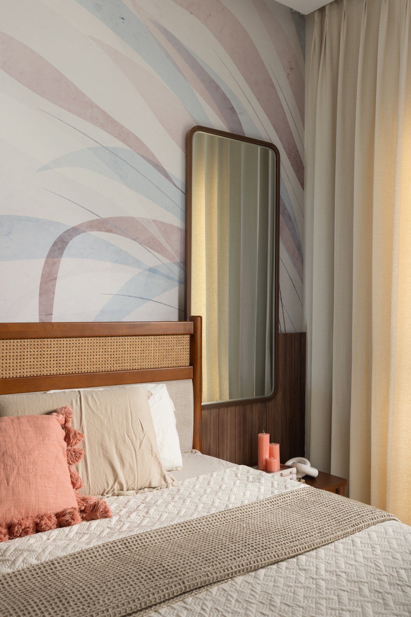 The master bedside vignette, its tall mirror and coral candles set against the mural's soft palette