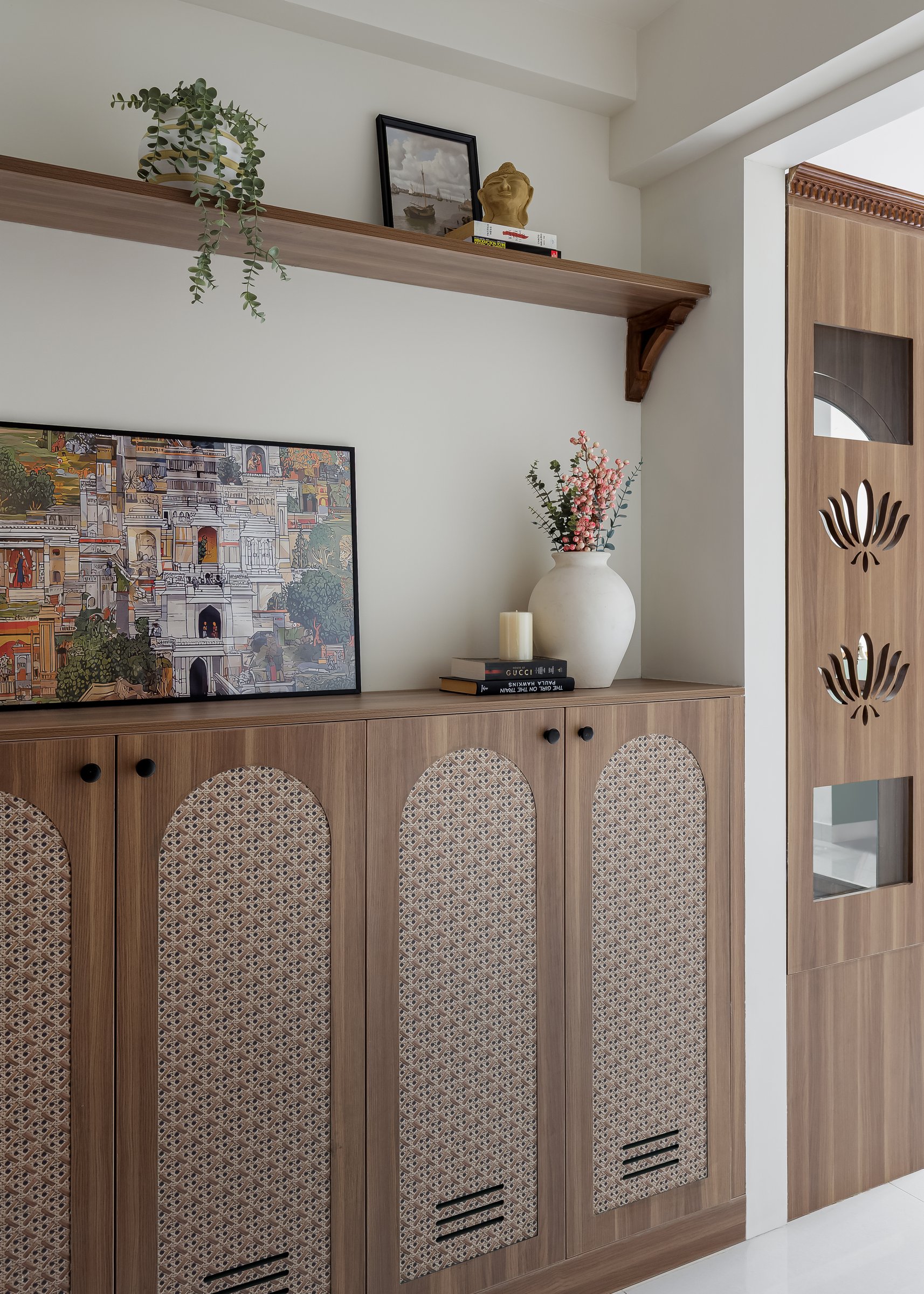 The foyer, where a walnut-toned shoe cabinet with arched cane inserts sets the home's material palette