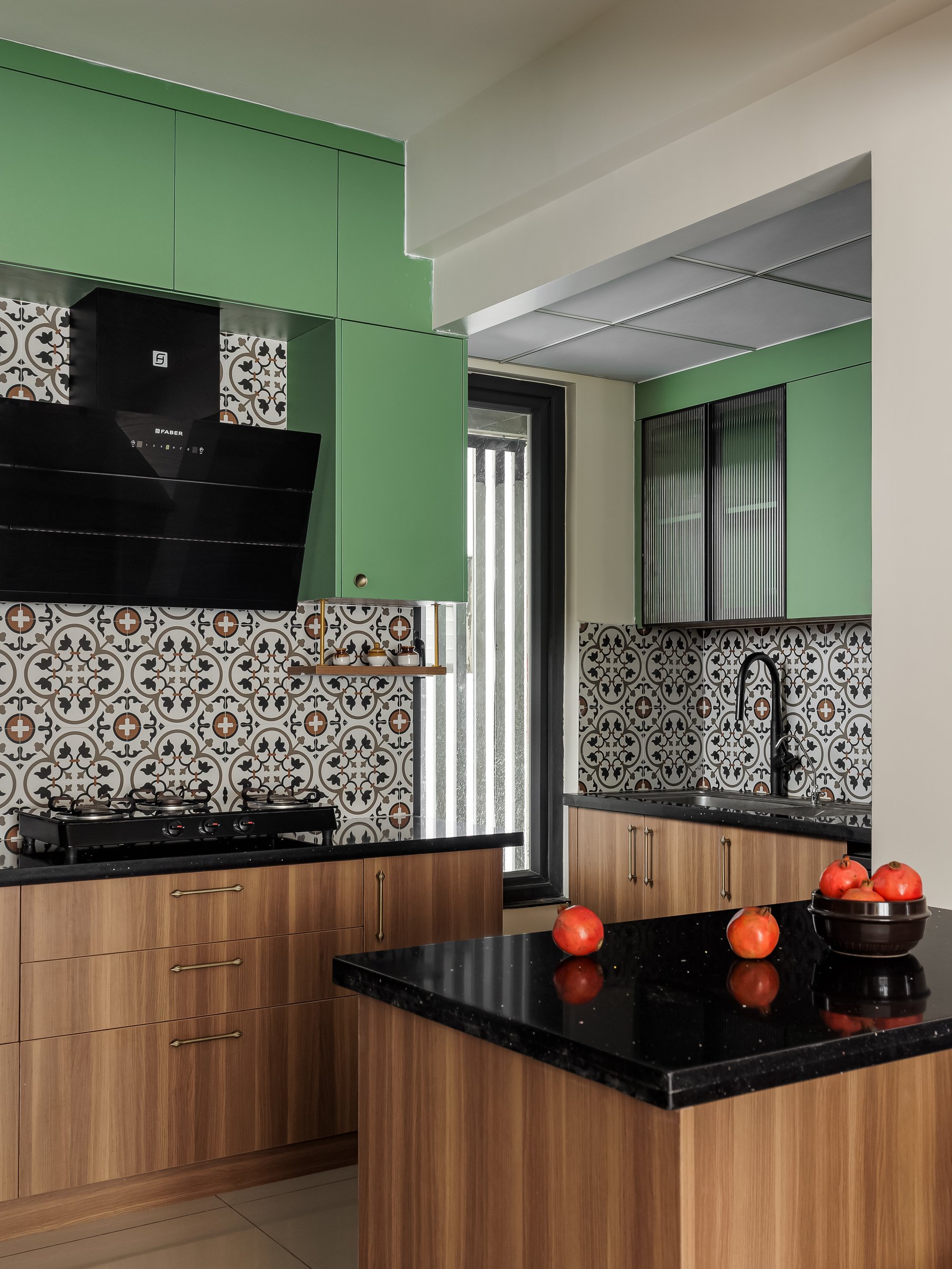 The prep counter, its black stone top and slim brass-toned pulls carrying the home's Indian detailing