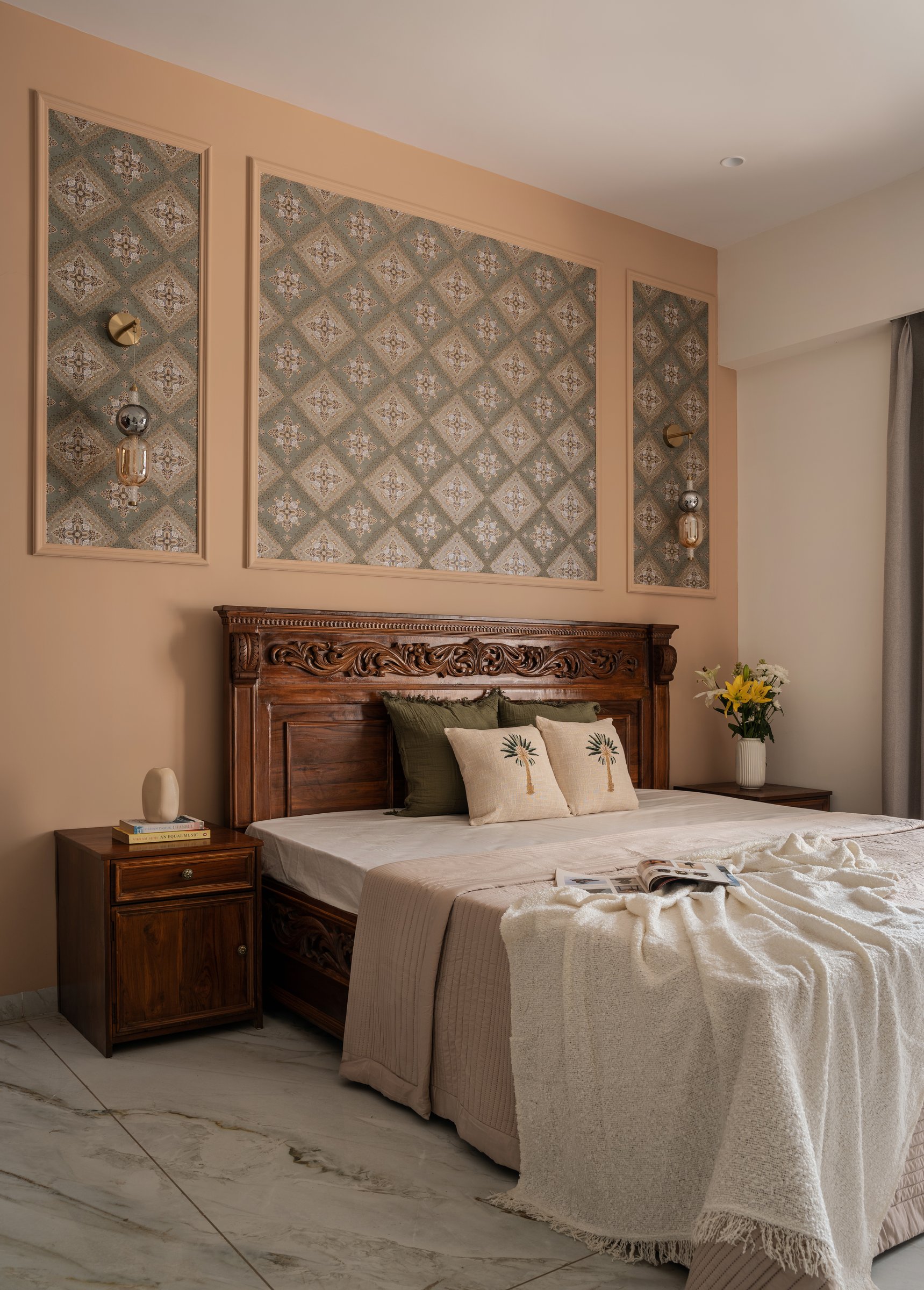 The master bedroom, where a carved teak headboard meets a peach wall composed as a triptych of patterned panels