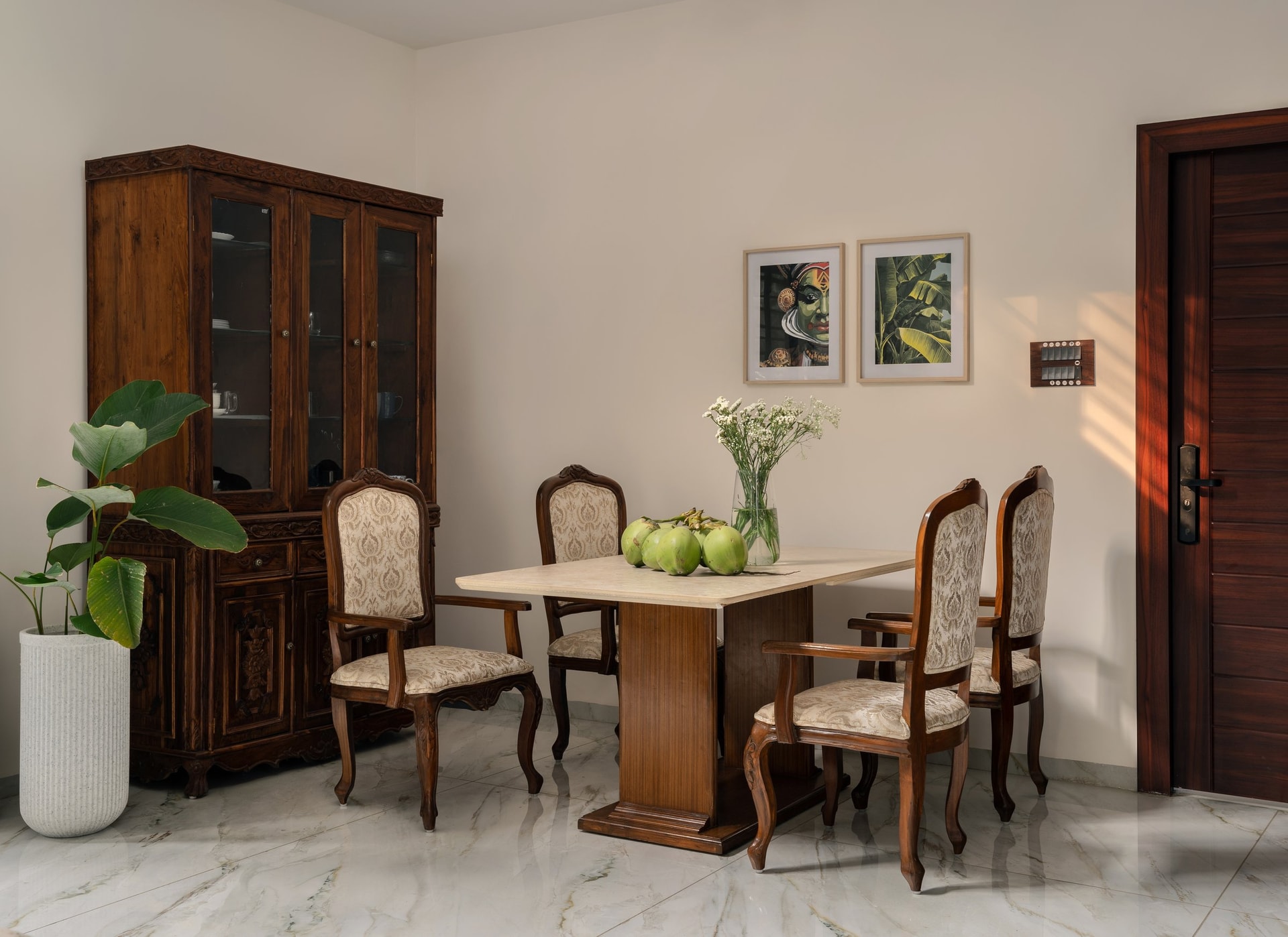 The dining area, where a stone-topped table on a teak pedestal sits alongside a heirloom glazed cabinet