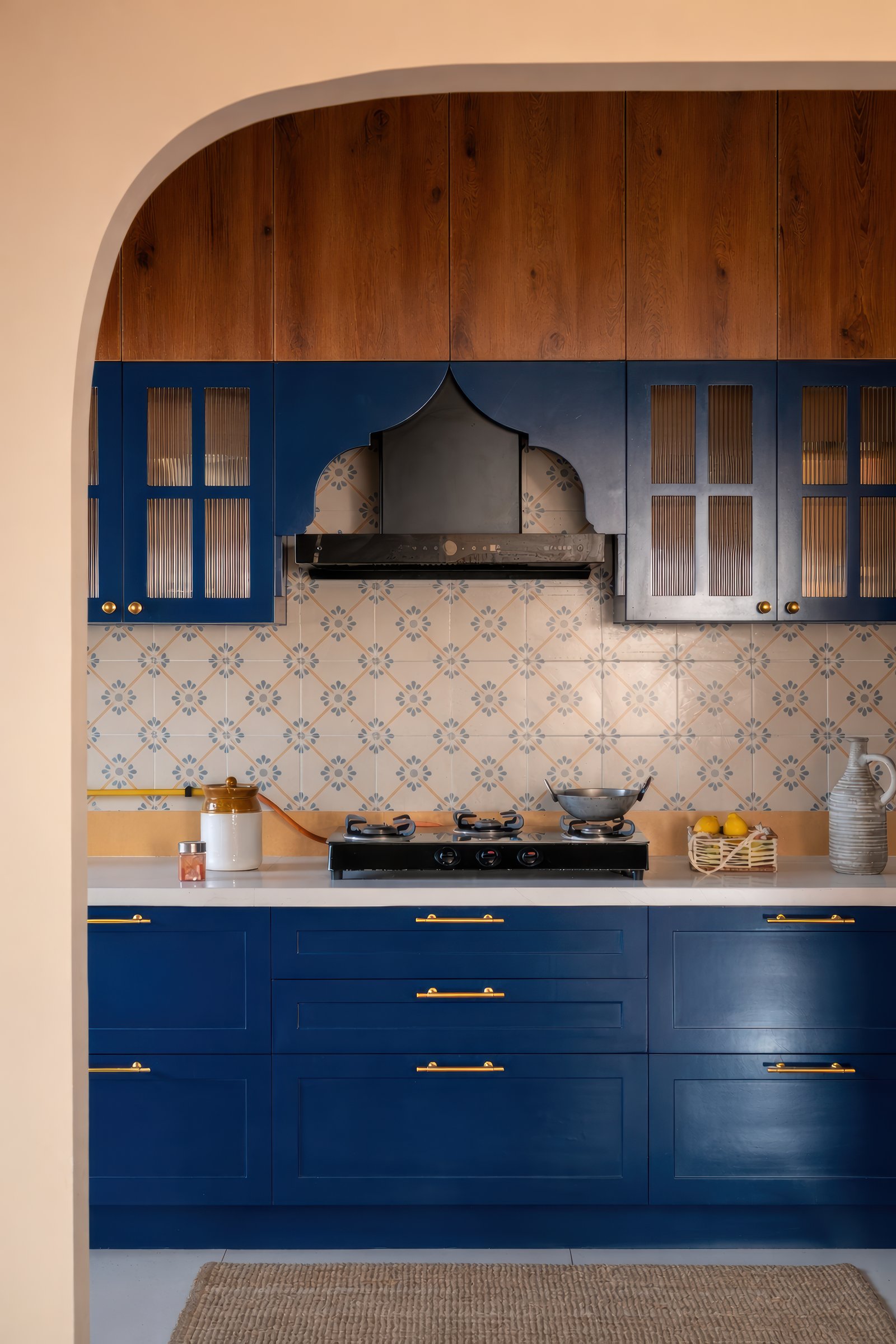 The kitchen, where deep blue cabinetry, brass pulls, and patterned encaustic-style tiles bring in a gentle vintage character
