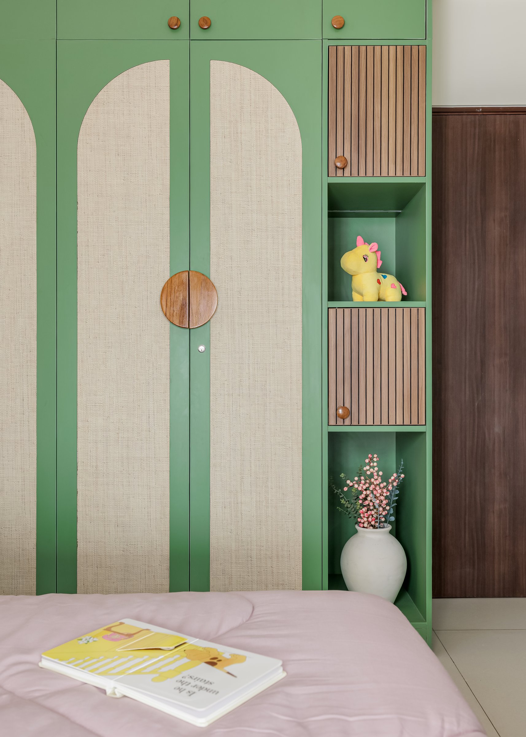 The joinery detail, with circular wooden knobs, slatted panels, and open shelving for soft toys