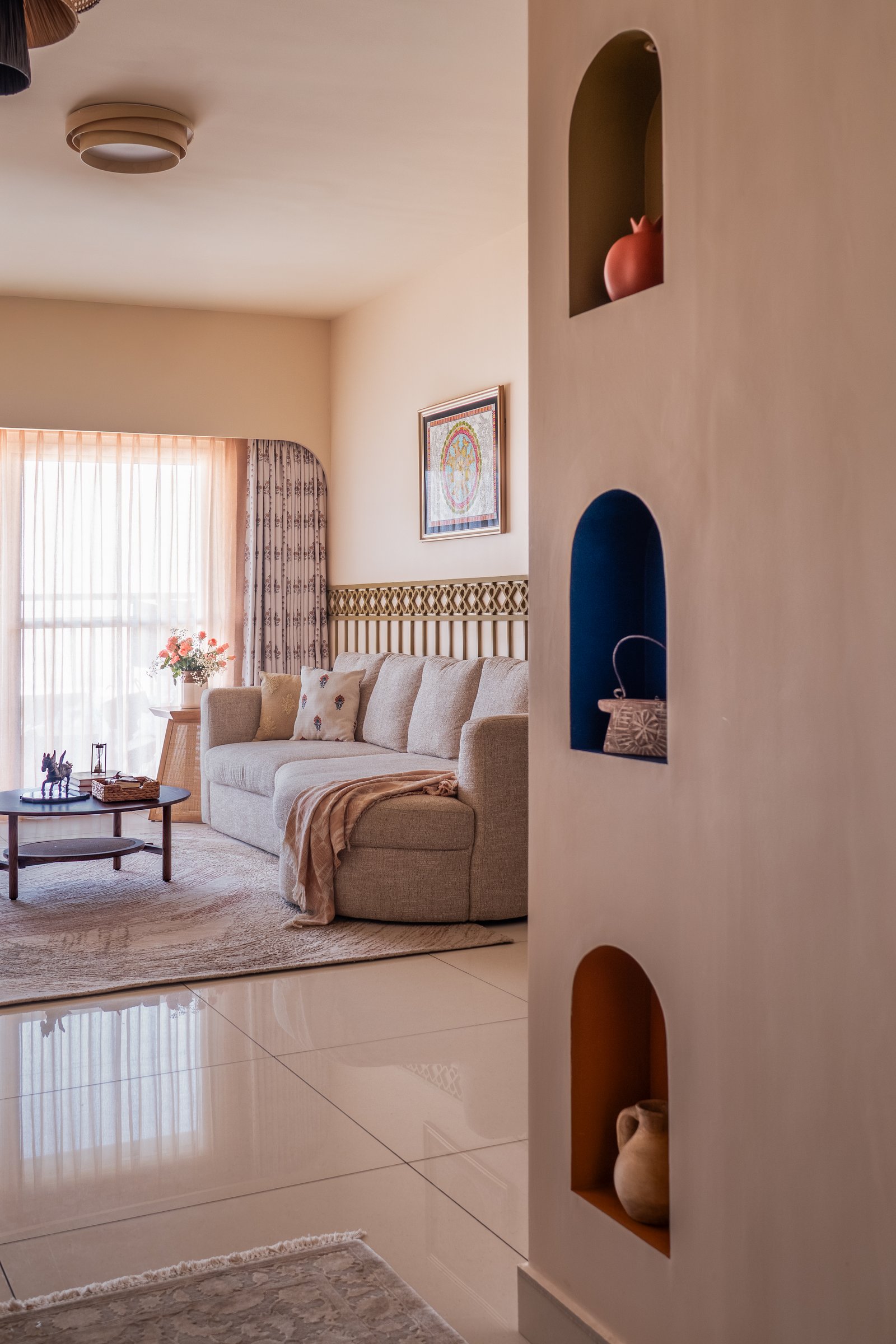 The living room, where small niches painted in deep blue, terracotta, and ochre introduce cultural reference without overwhelming the calm neutral palette