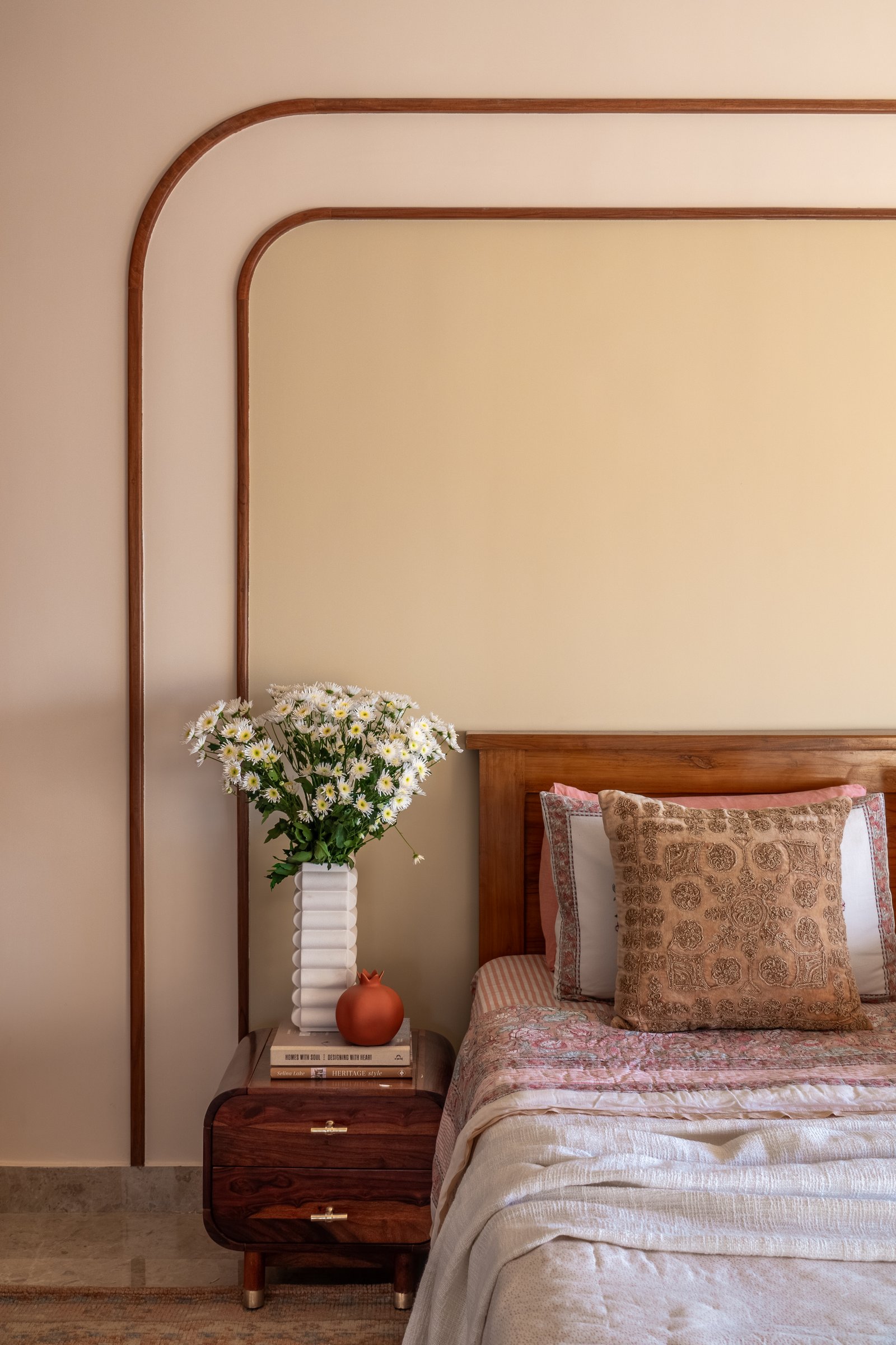 The master bedroom, where concentric rounded wooden frames outline the headboard wall in a soft echo of the home's recurring arches