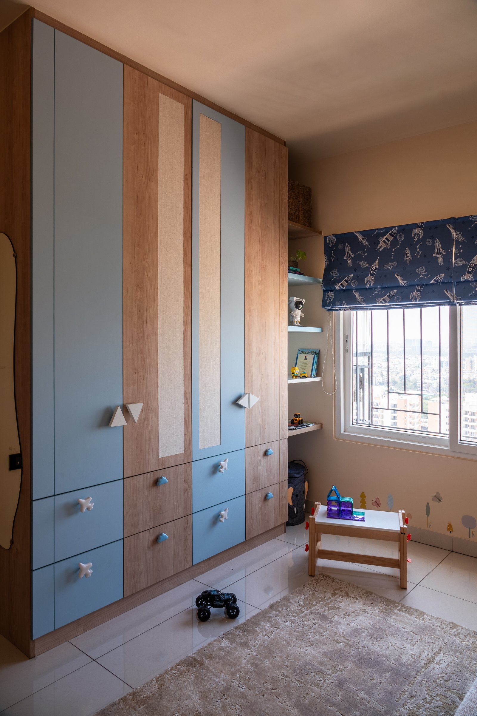 The kids room wardrobe, where dusty blue and warm wood panels combine with woven inserts for a durable interpretation of cane
