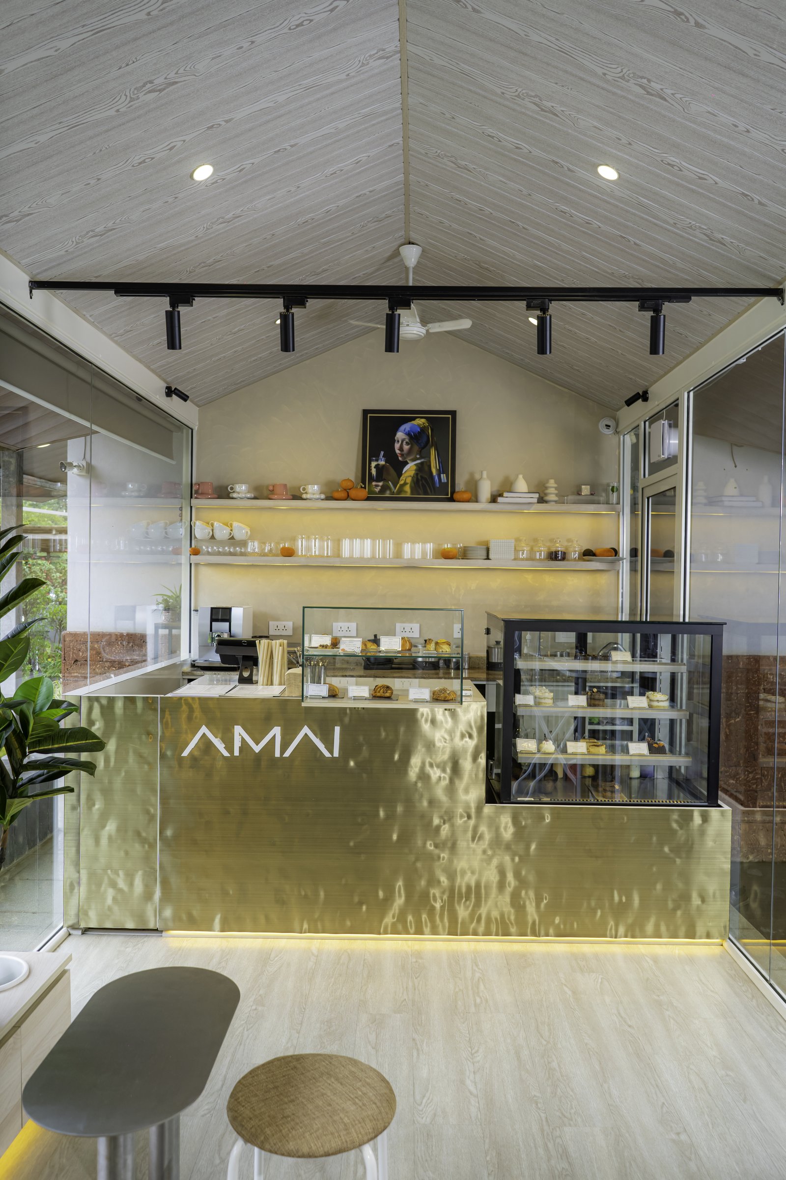 The counter wall, where concealed warm light behind open shelves lifts the brass face into focus