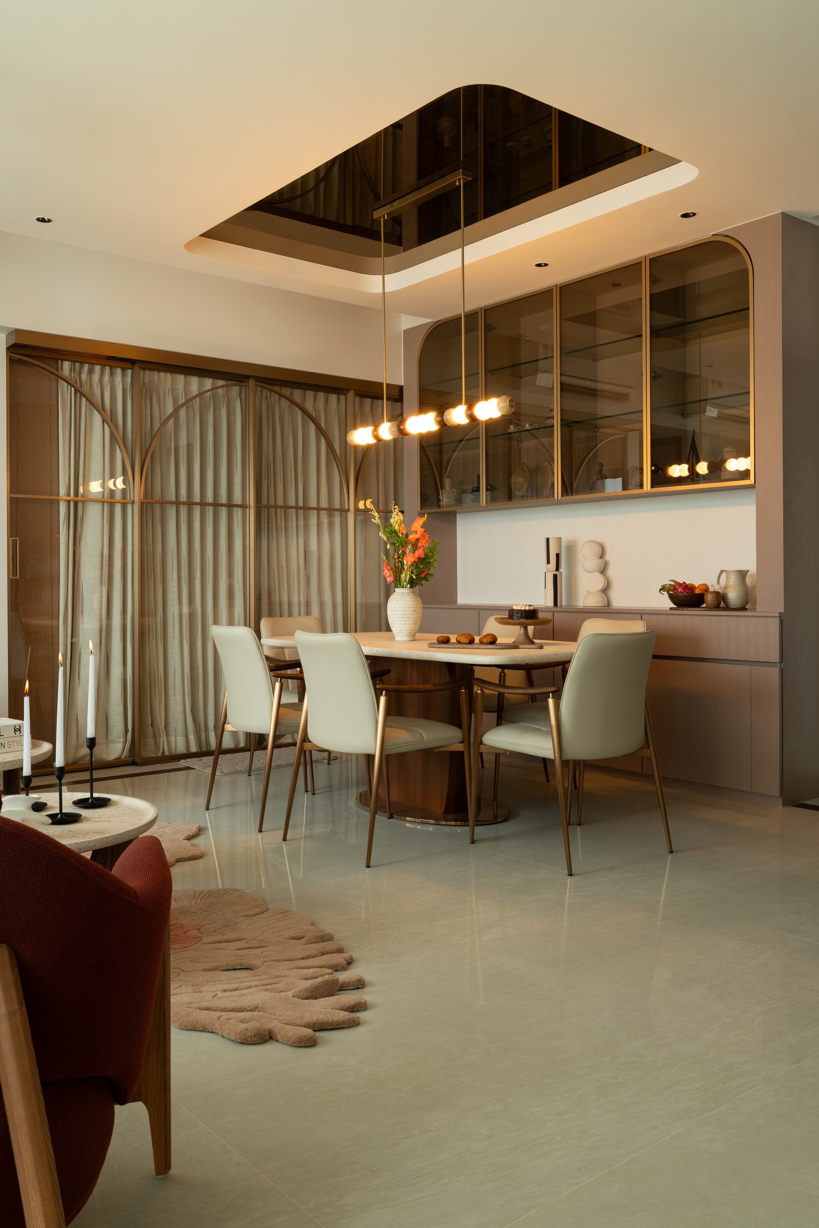 The dining area, with its walnut oval table, bronze pedestal base, and recessed bronze mirror inset in the ceiling