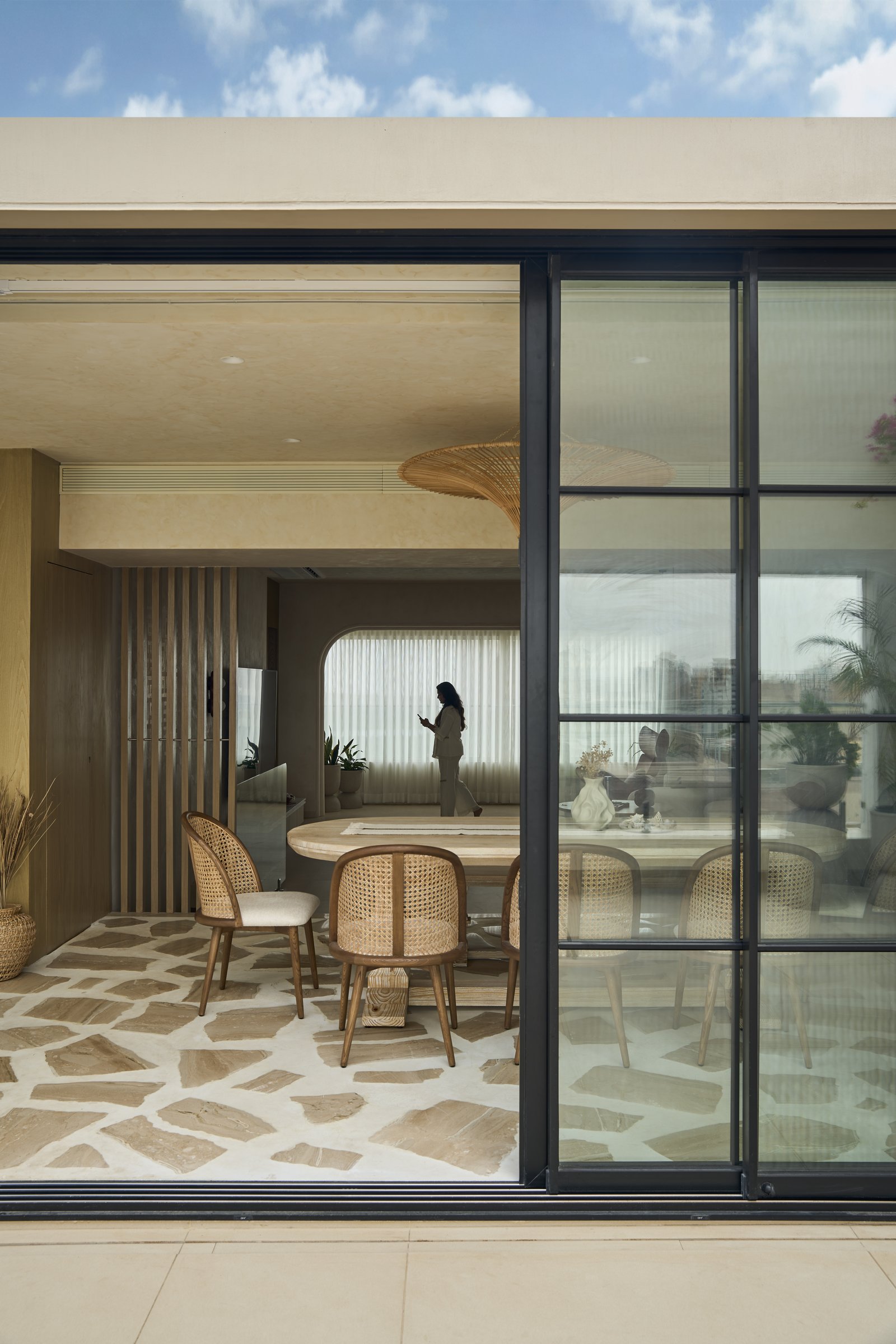 The dining zone opens through steel-framed sliding glazing onto a flagstone-floored terrace