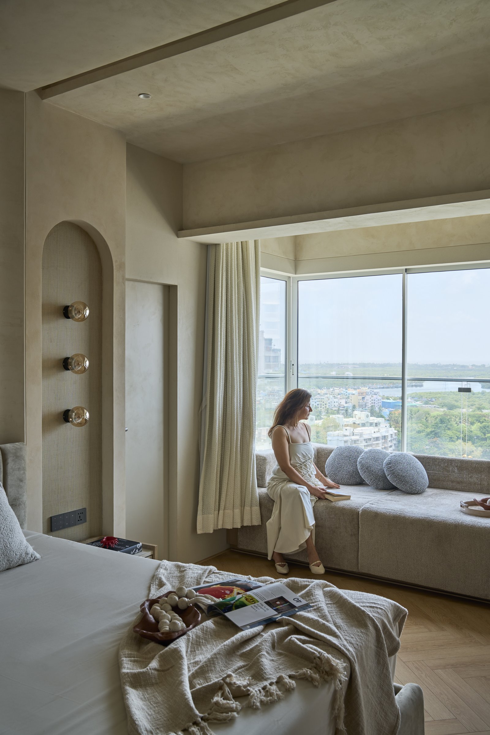 The principal bedroom, where a deep upholstered window seat opens to a wide horizon of greenery and city