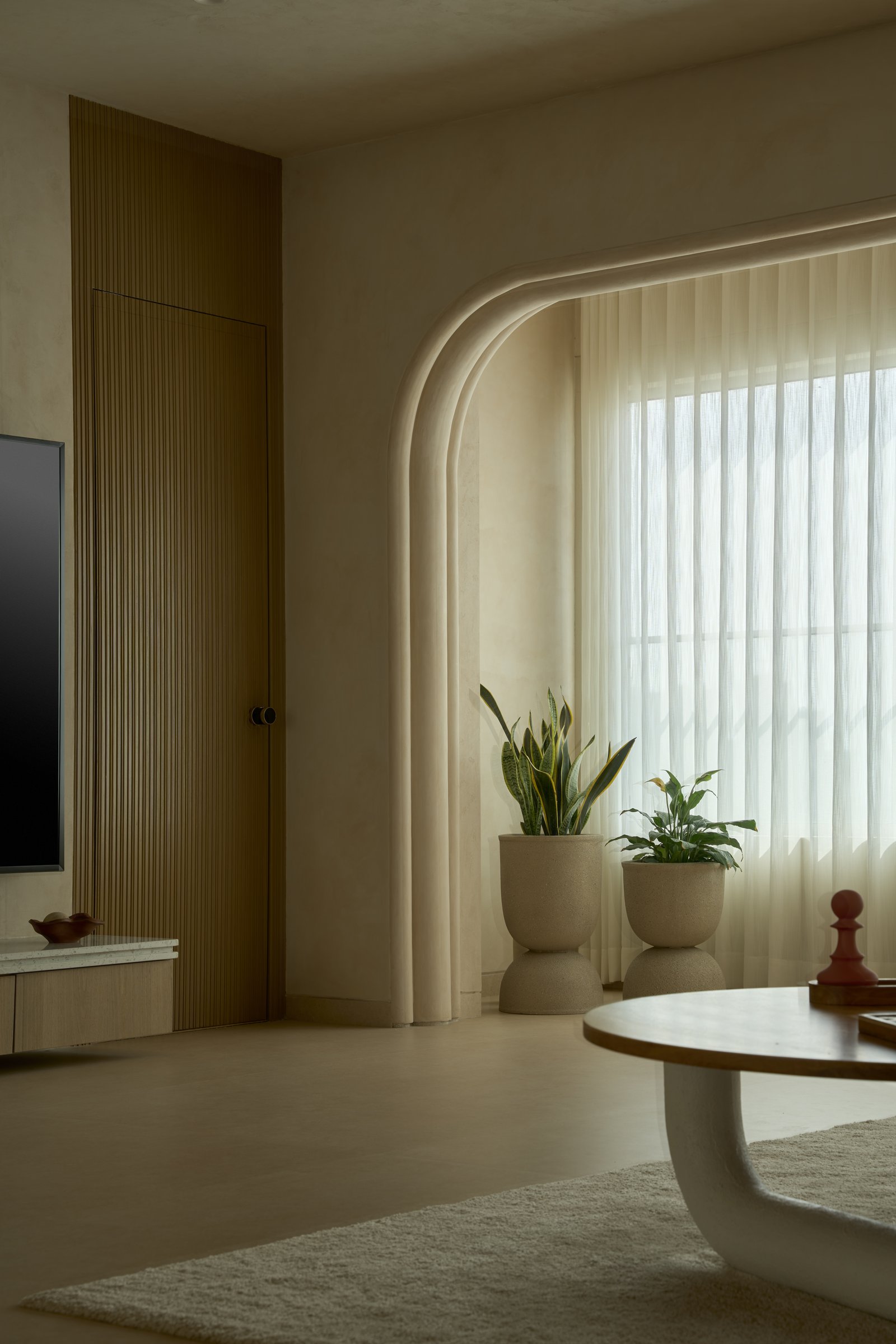 A slatted wood door and arched window opening establish the room's rhythm of curves and verticals