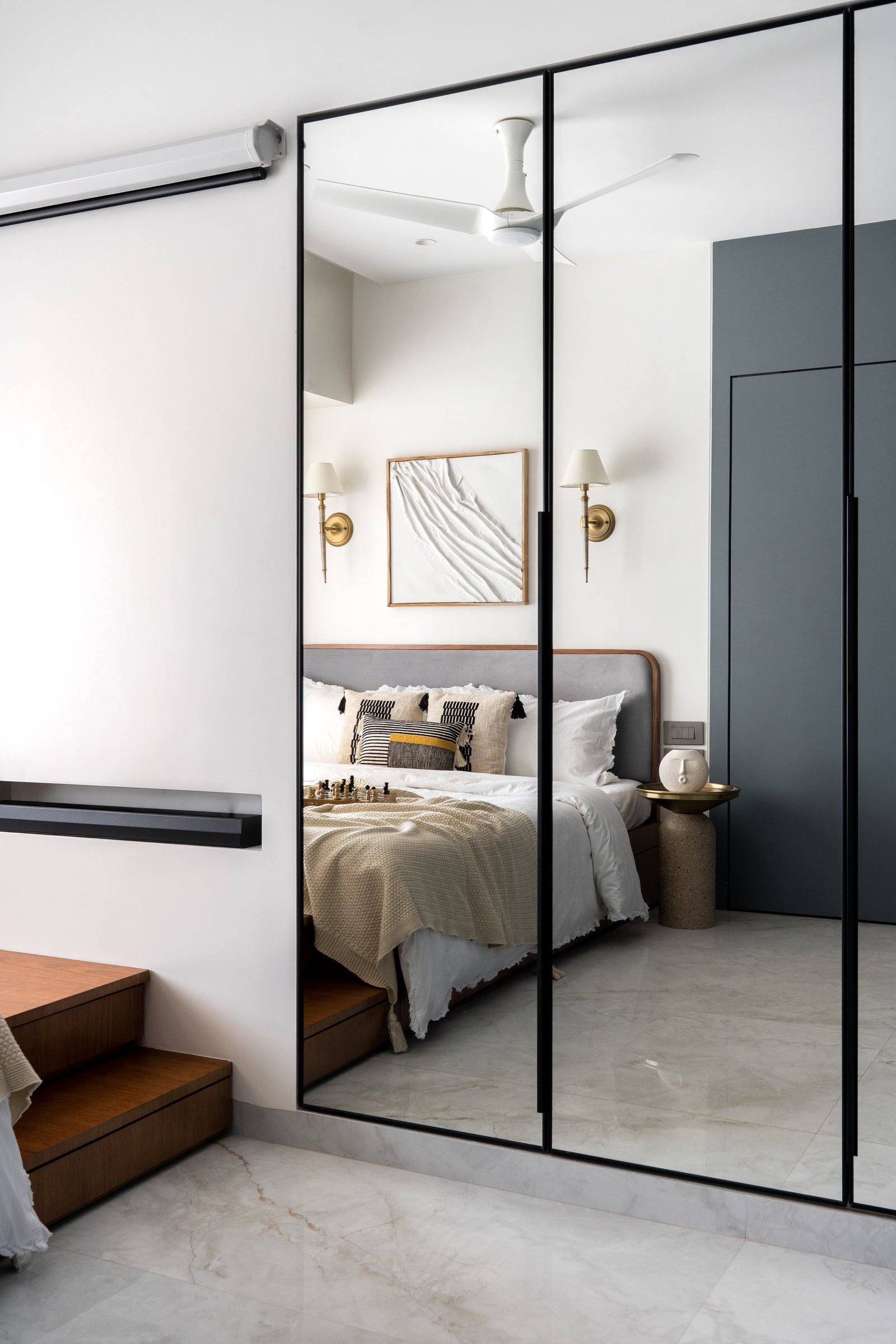 A tall mirrored panel opposite the bed doubles the room's depth