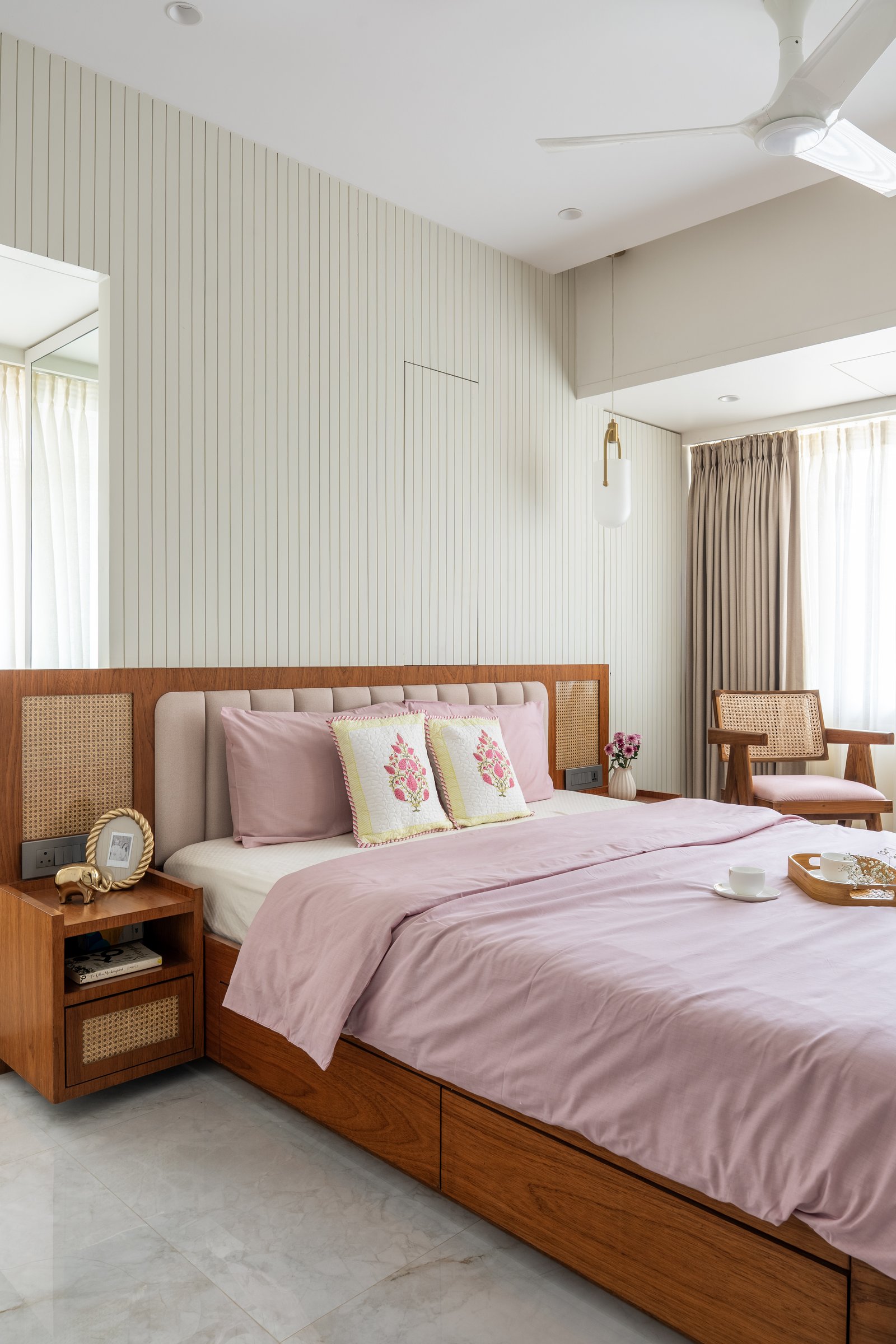 The master bedroom, where a slatted ivory wall meets a teak platform bed with cane-inset side panels