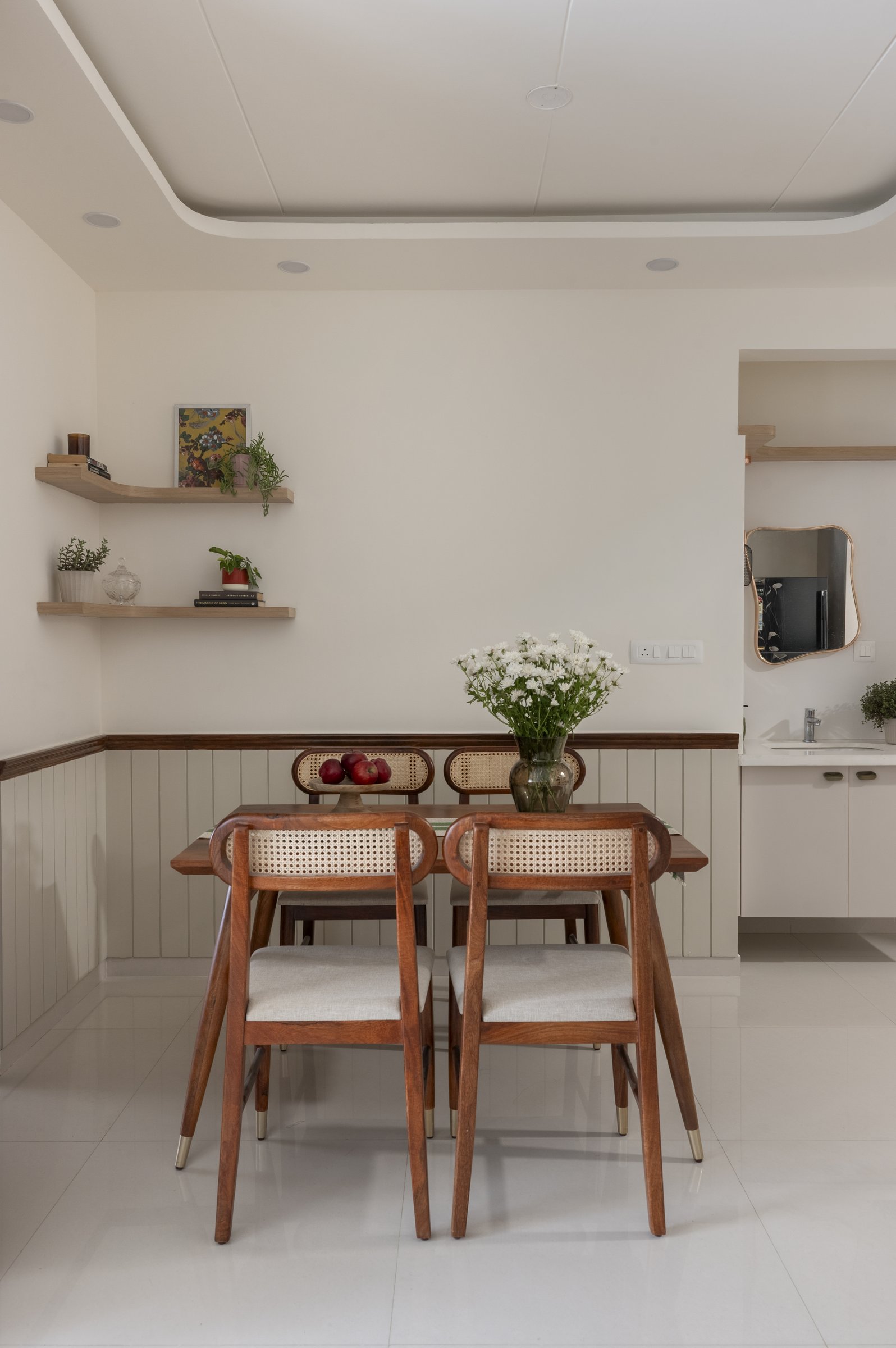The dining area, where cane-back chairs and a pair of floating shelves quietly close the composition