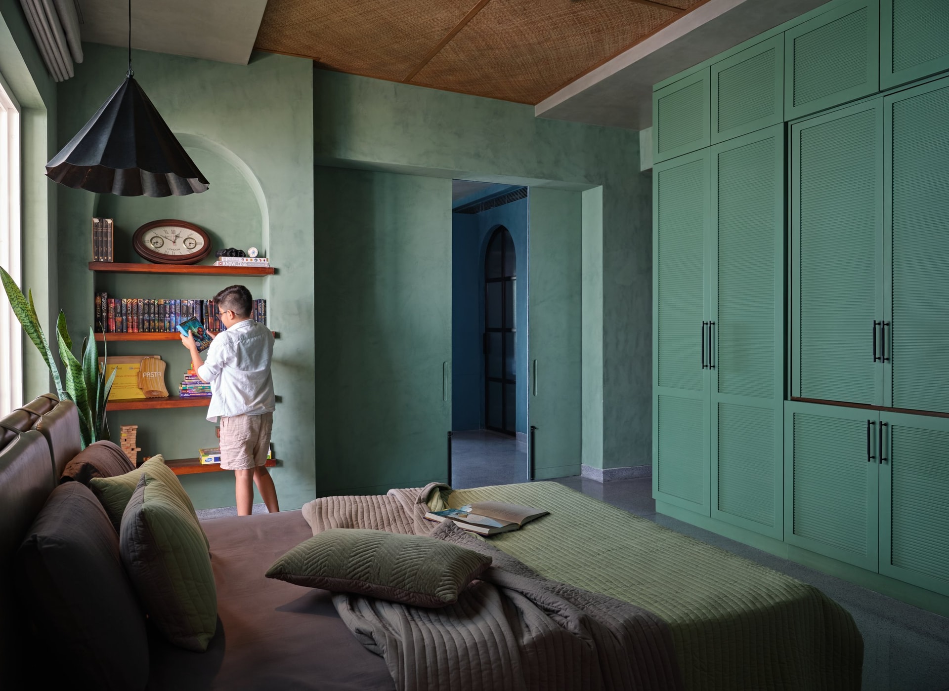 The children's bedroom, where sage lime-wash and fluted louvred wardrobes frame a private library niche