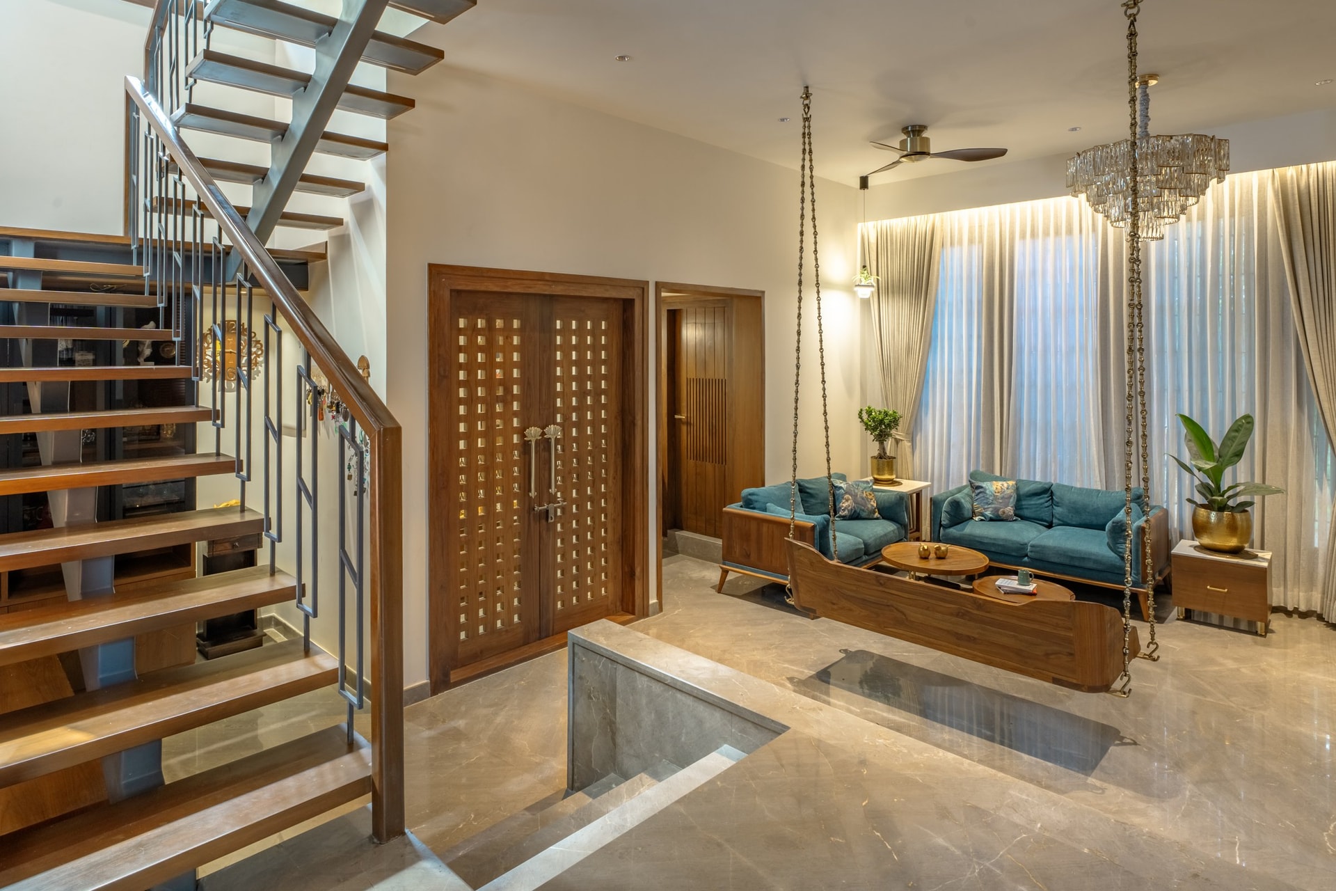 The double-height living volume, anchored by a teak swing on beaded brass rods and a metal-and-timber staircase along one edge