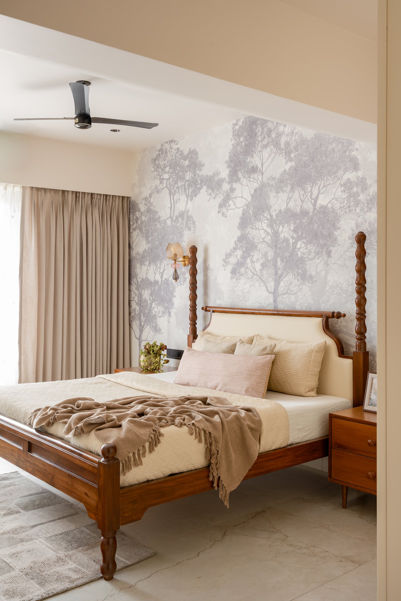 The primary bedroom, where a wooden four-poster bed sits against a soft grey-toned forest mural