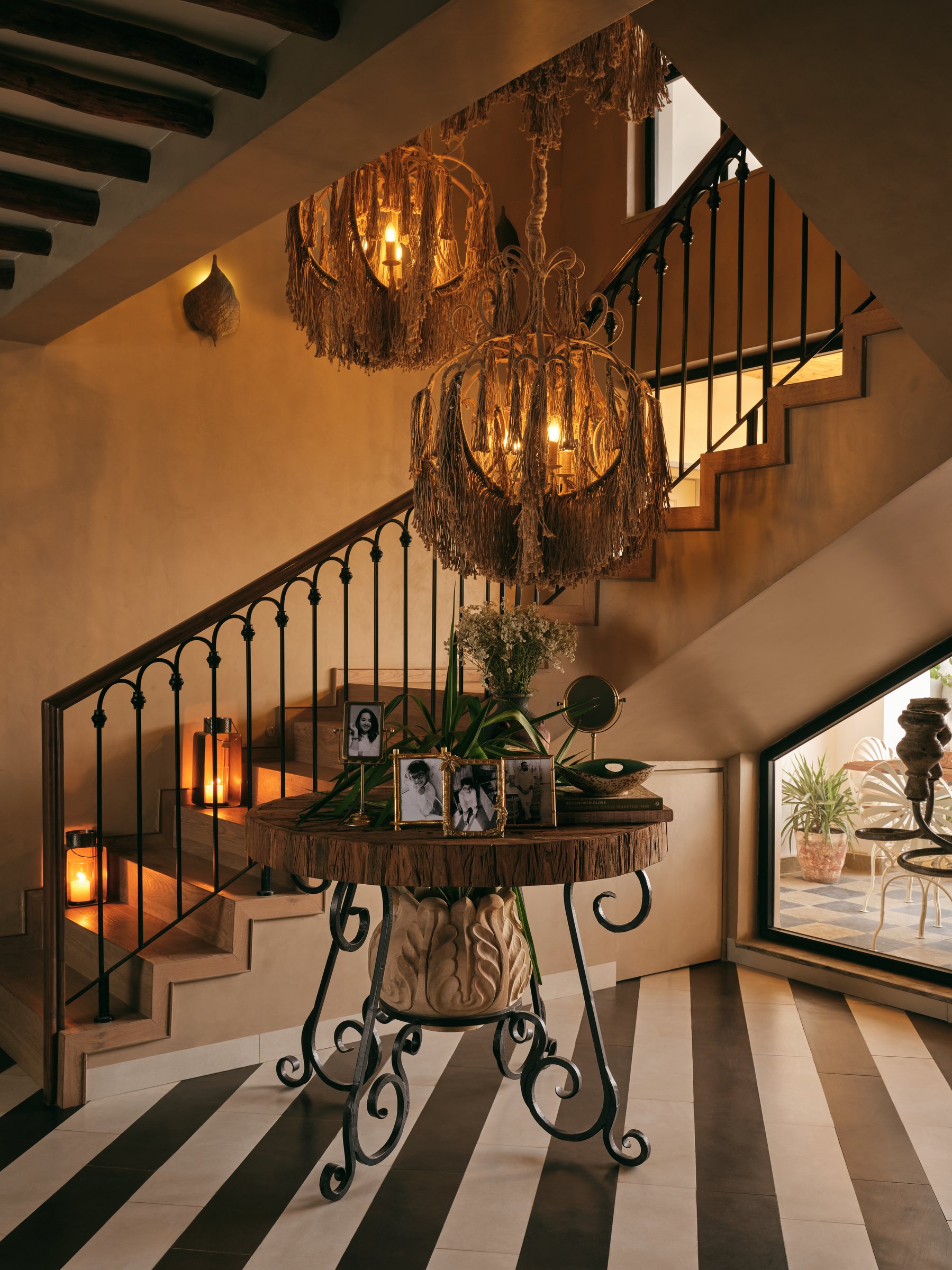 The staircase, where diagonal striped flooring meets cascading fibrous chandeliers above a reclaimed-wood console