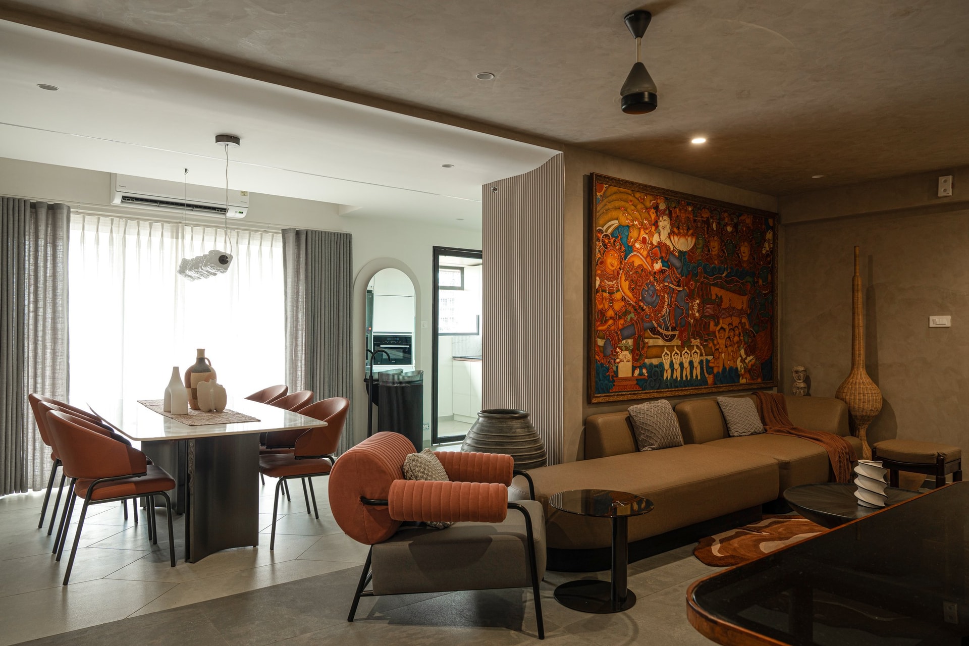 The living and dining rooms unfold as a single social space, with a large Kerala mural anchoring the seating wall