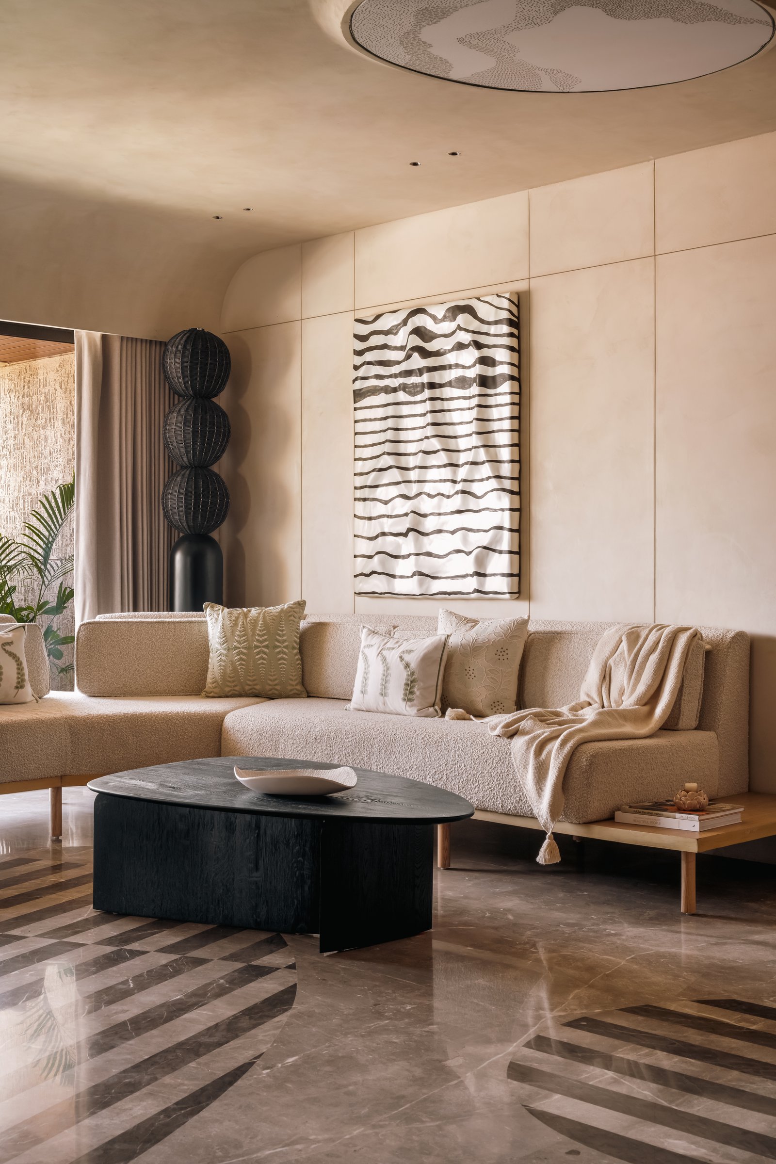 The informal living area, with its sculpted ceiling disc and bouclé sofa set against a panelled plaster wall