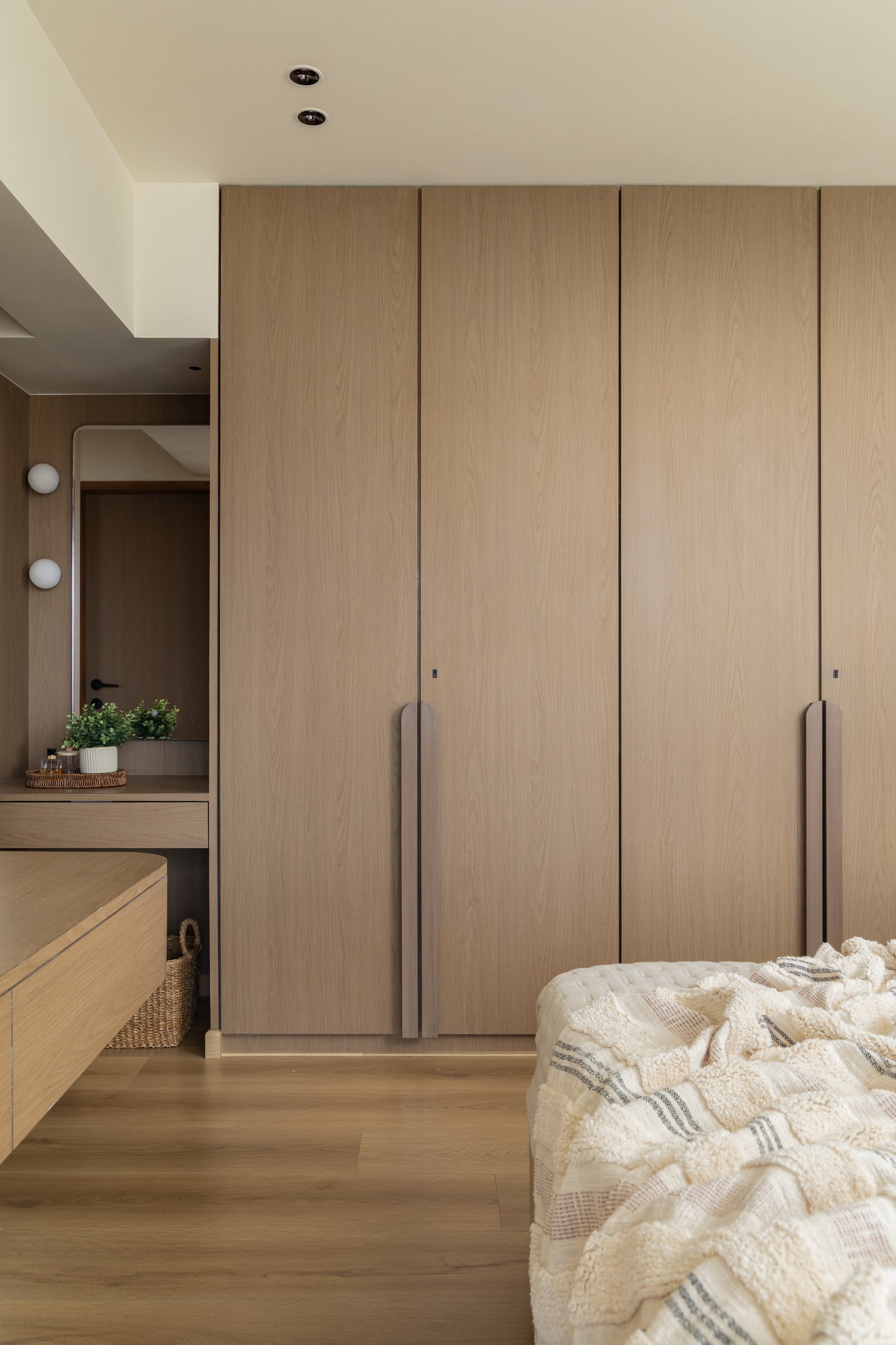 The wardrobe run with its slender curved pulls, and a compact dressing corner slipped in beside it