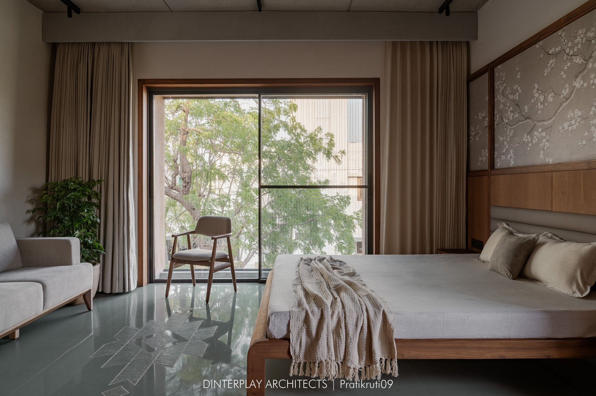 The master bedroom, softened by a blossom-branch panel behind the bed and views to the tree line