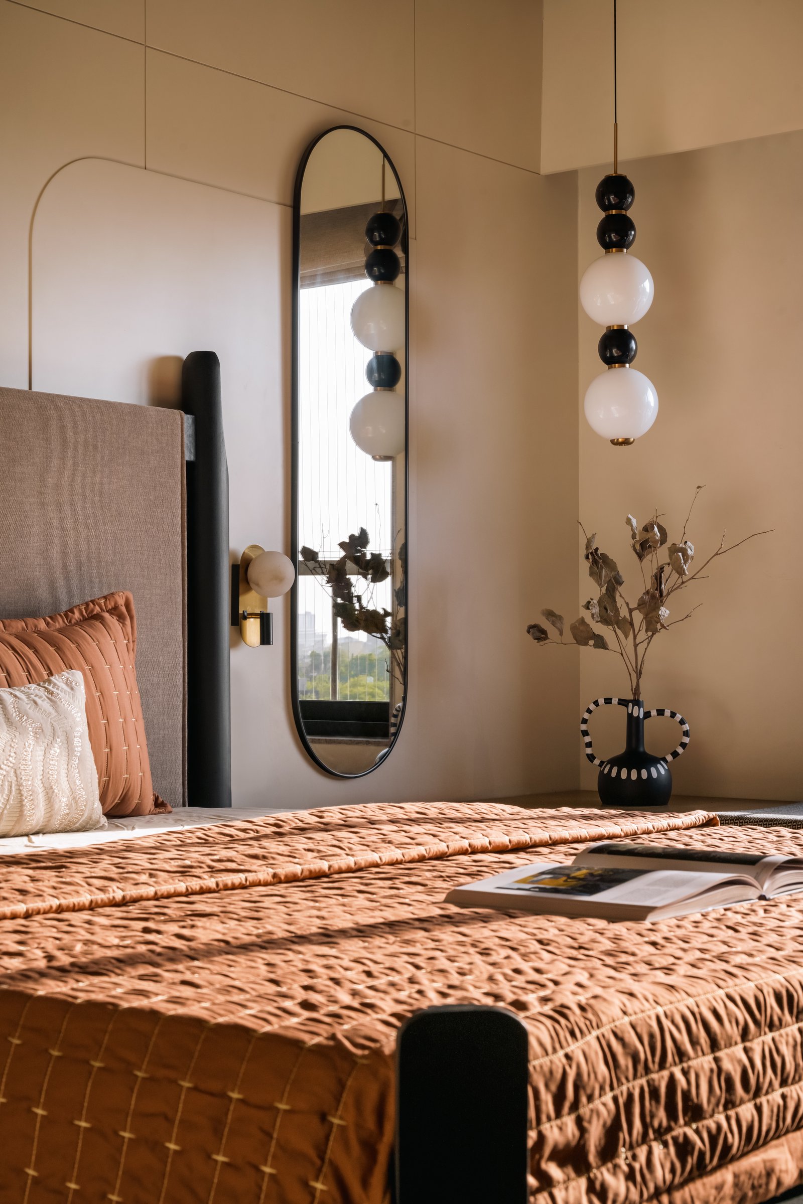 An oval mirror doubles the mural's presence in the second bedroom, with alabaster sconces sitting in the negative space
