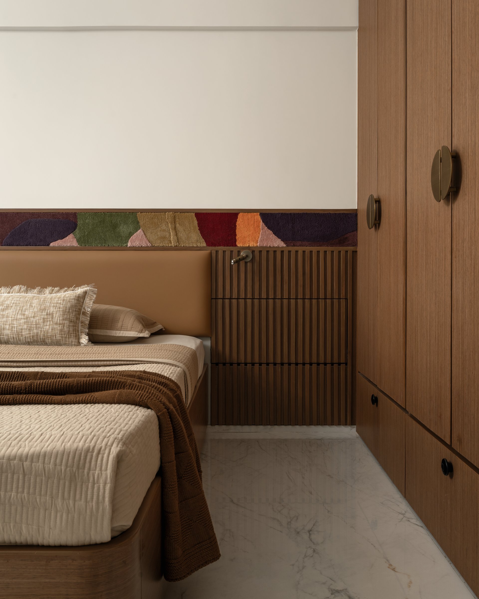 The wardrobe wall in warm-toned timber, fitted with sculptural metal pulls that read as small architectural details