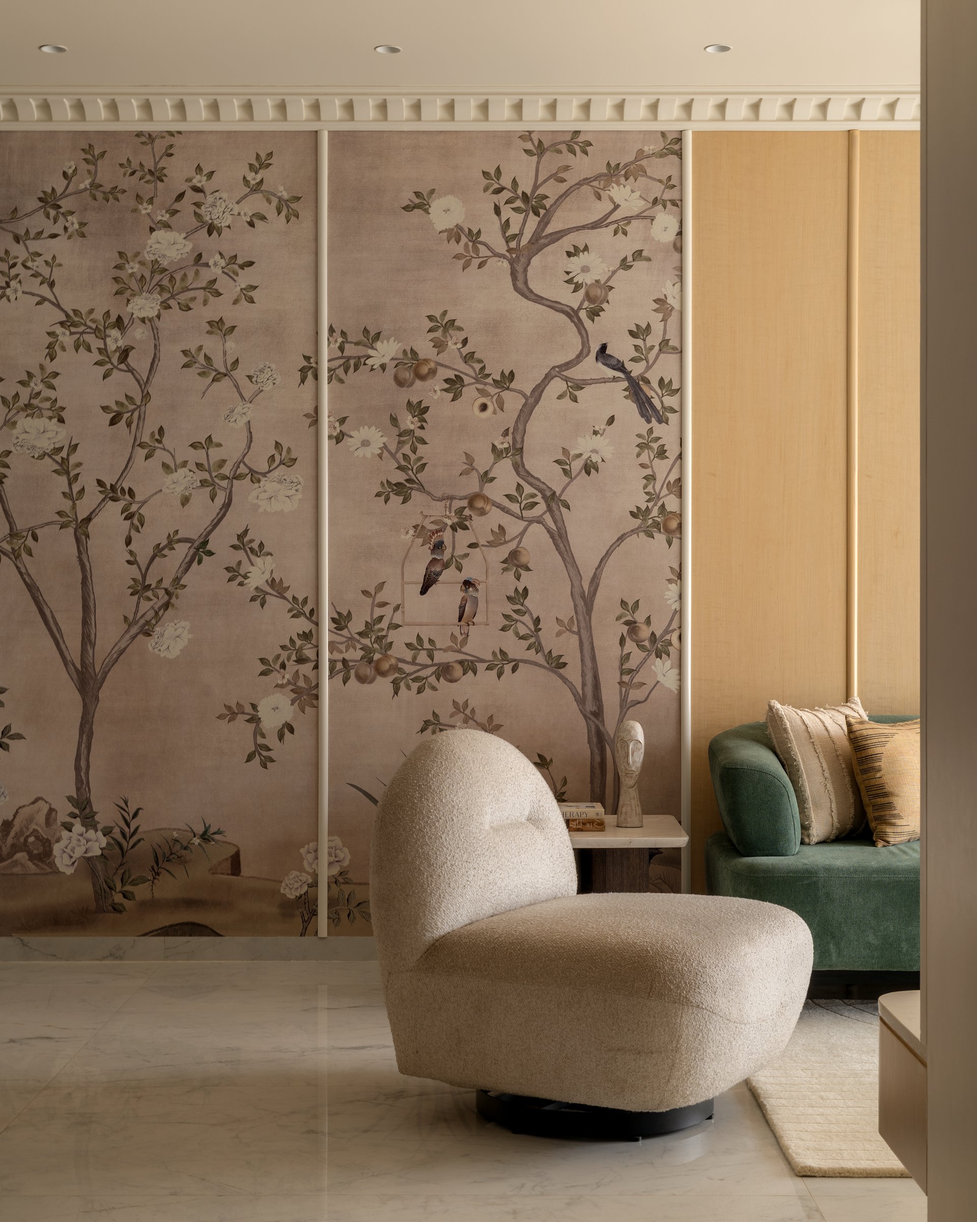 A curved bouclé lounge chair set against the chinoiserie panel that threads through the social spaces