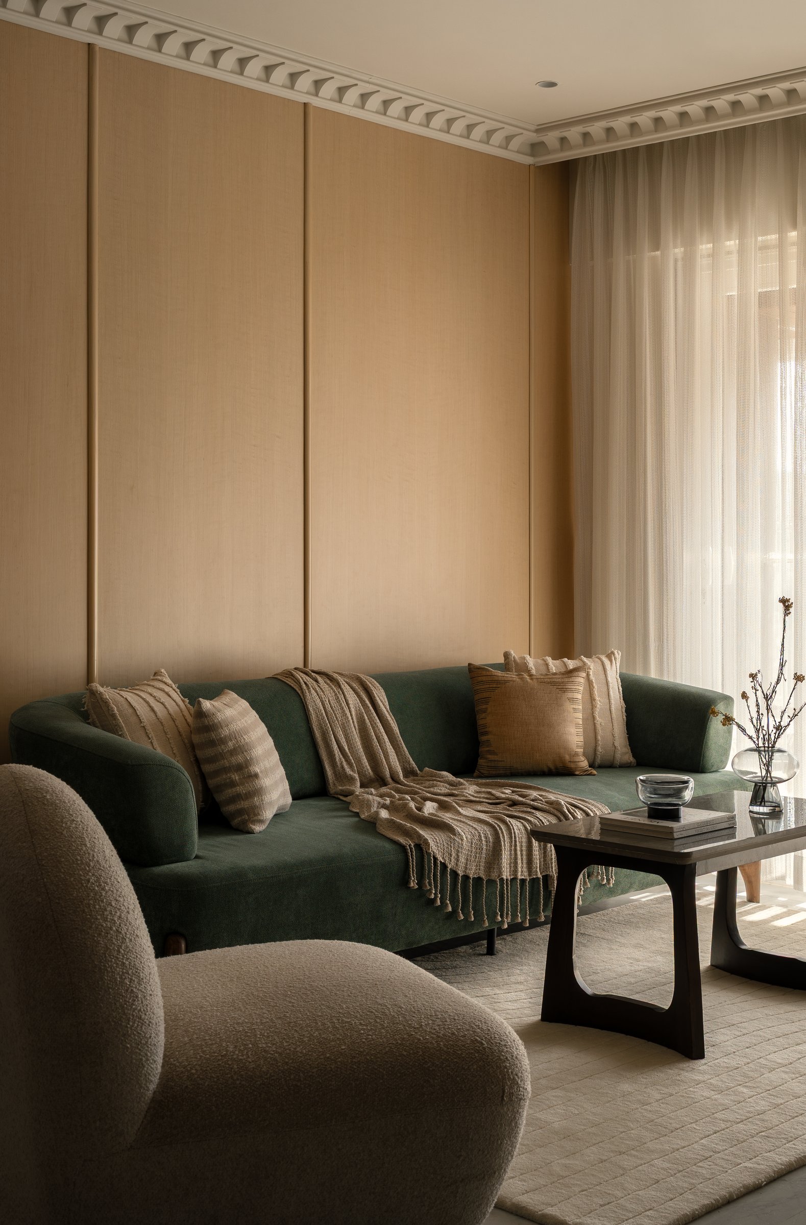 The deep green sofa set against fluted timber panelling, framed by the dentilled cornice above