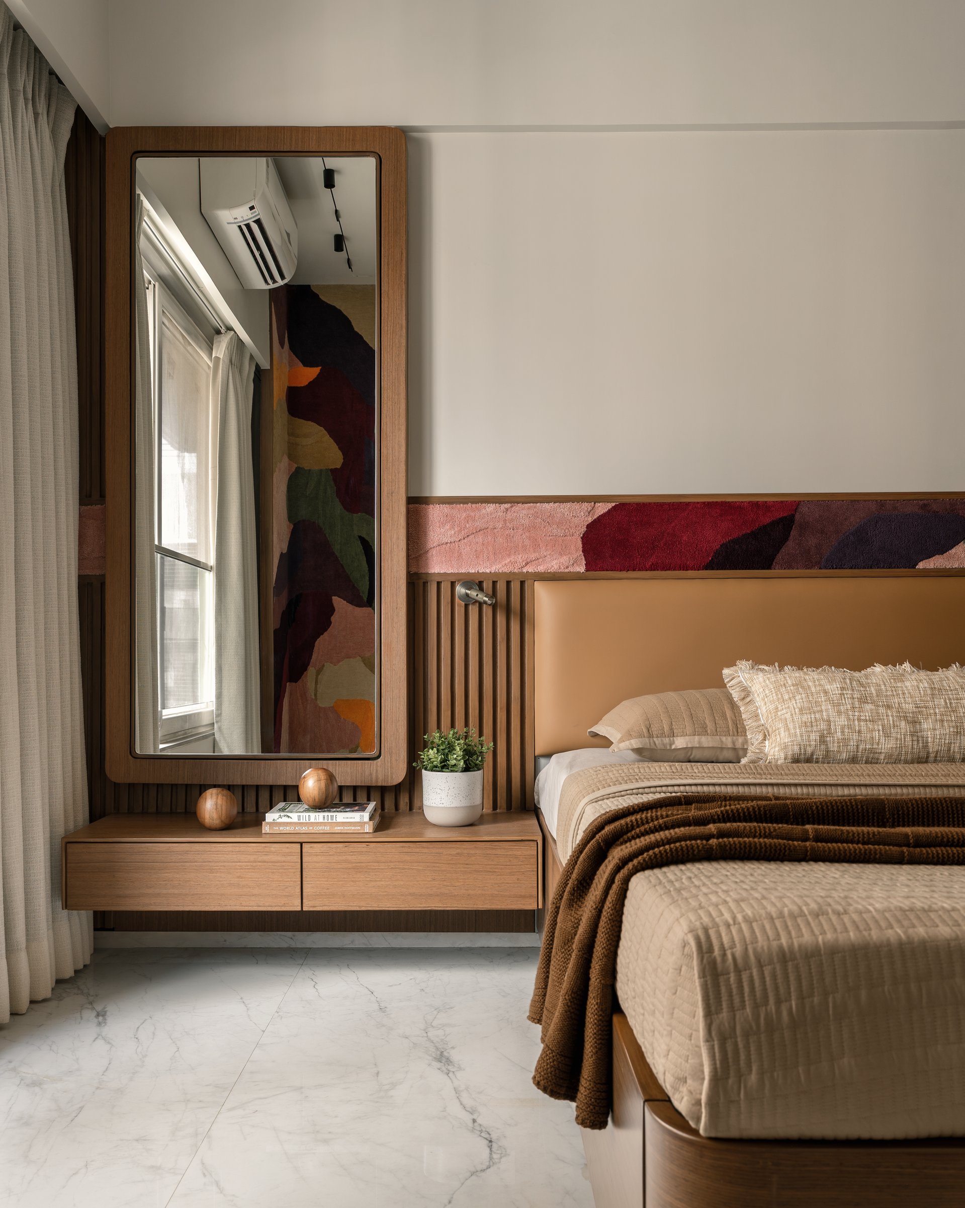 The primary bedroom, where a tan leather headboard and a strip of tufted textile art establish a warmer tonal register