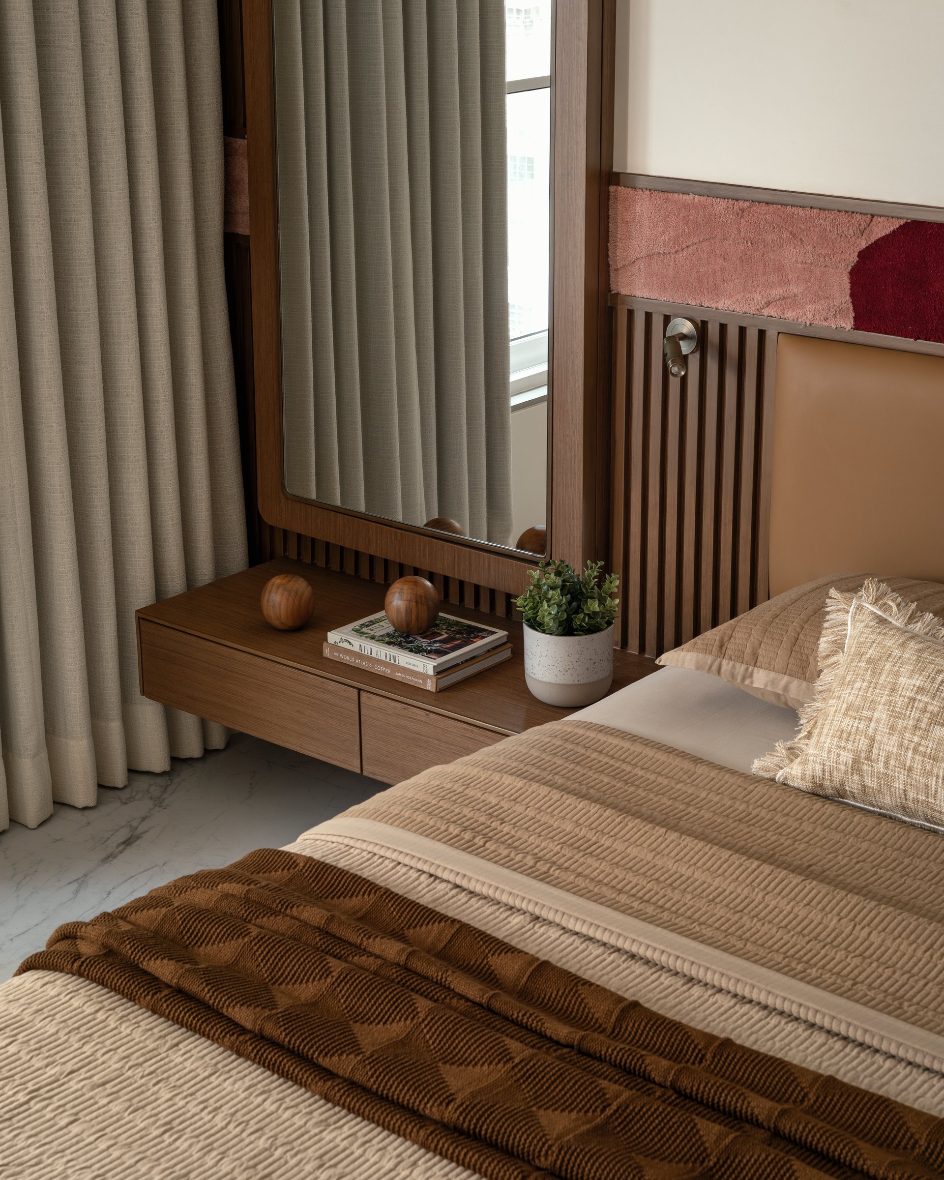 A closer view of the slatted timber panel and floating nightstand that integrate the dressing zone into the bed wall