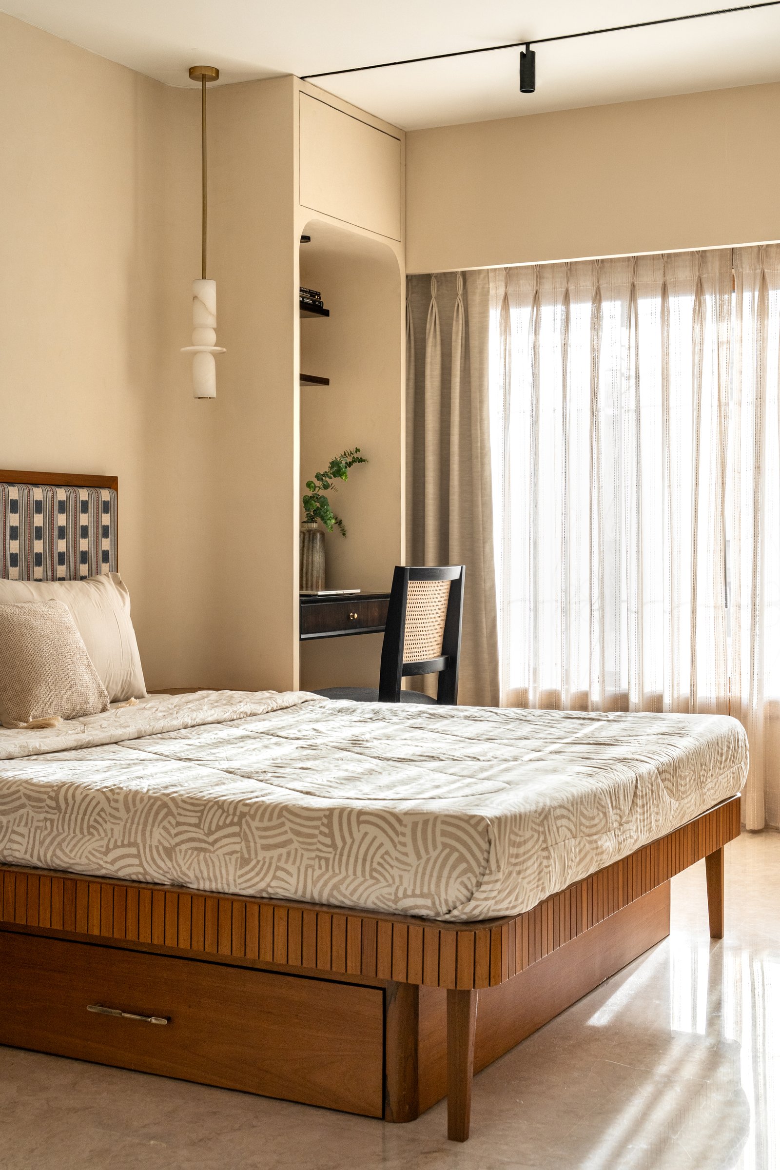 The second bedroom, with walls in soft champagne and a fluted timber bed anchored by a checkered upholstered headboard