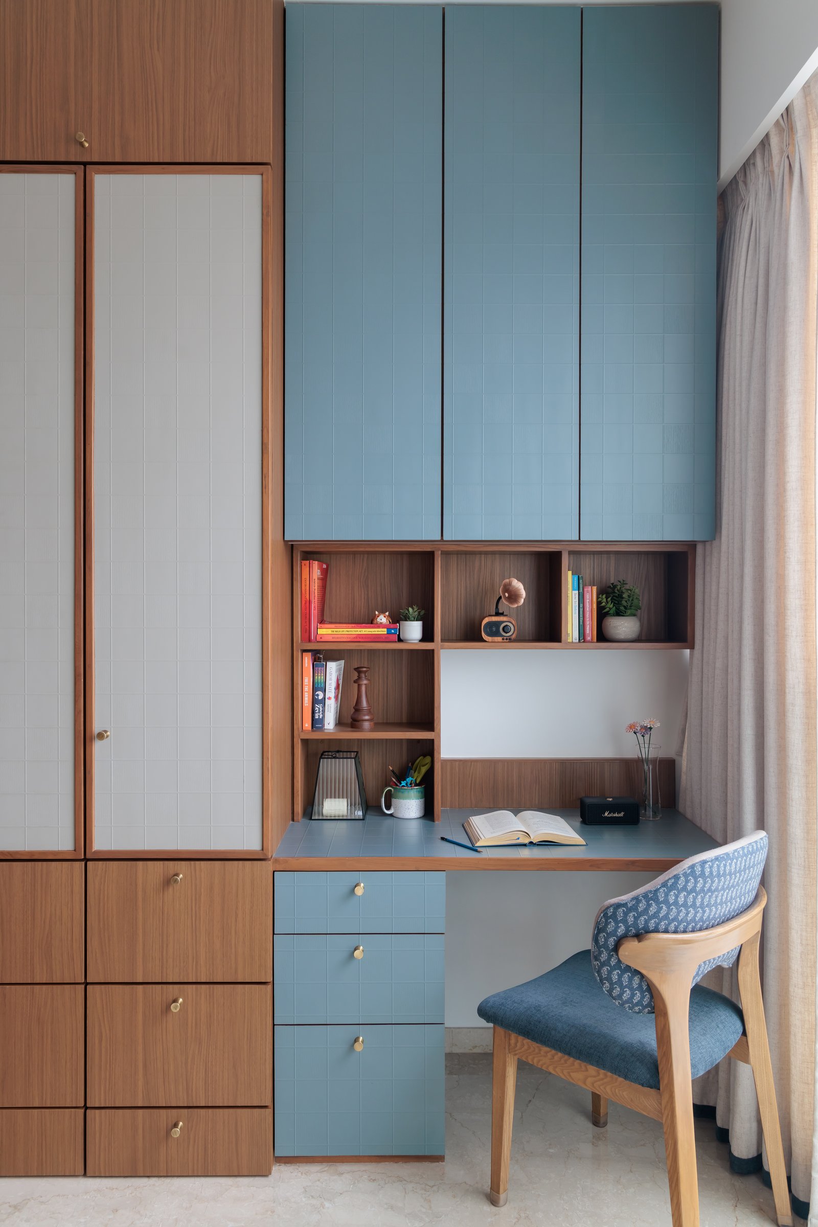 A compact study built into the joinery, where pale blue cabinets arrive against a backdrop of warm timber