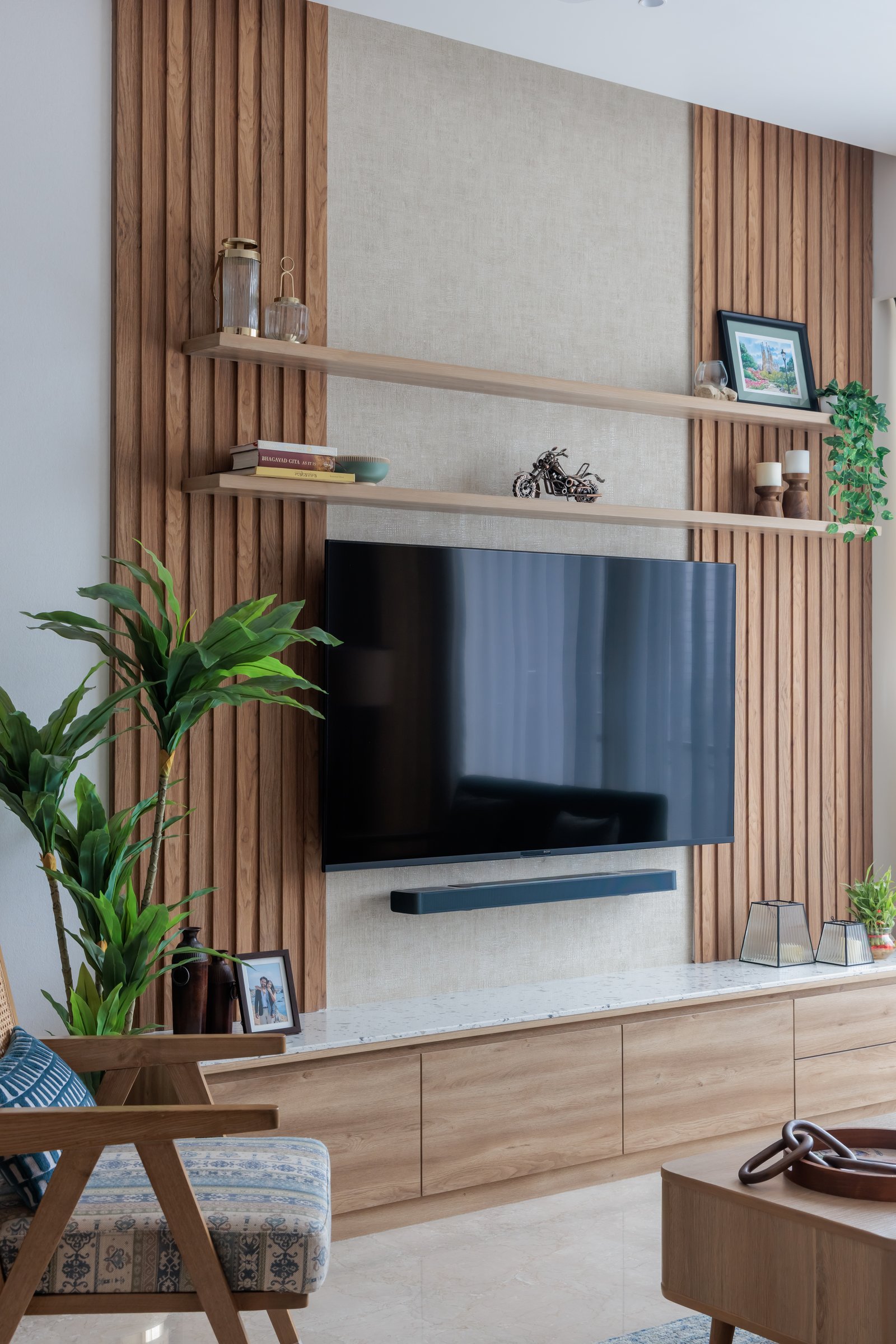 The media wall, with slatted timber panels flanking a linen-toned centre and floating shelves left partly bare for photographs still to come